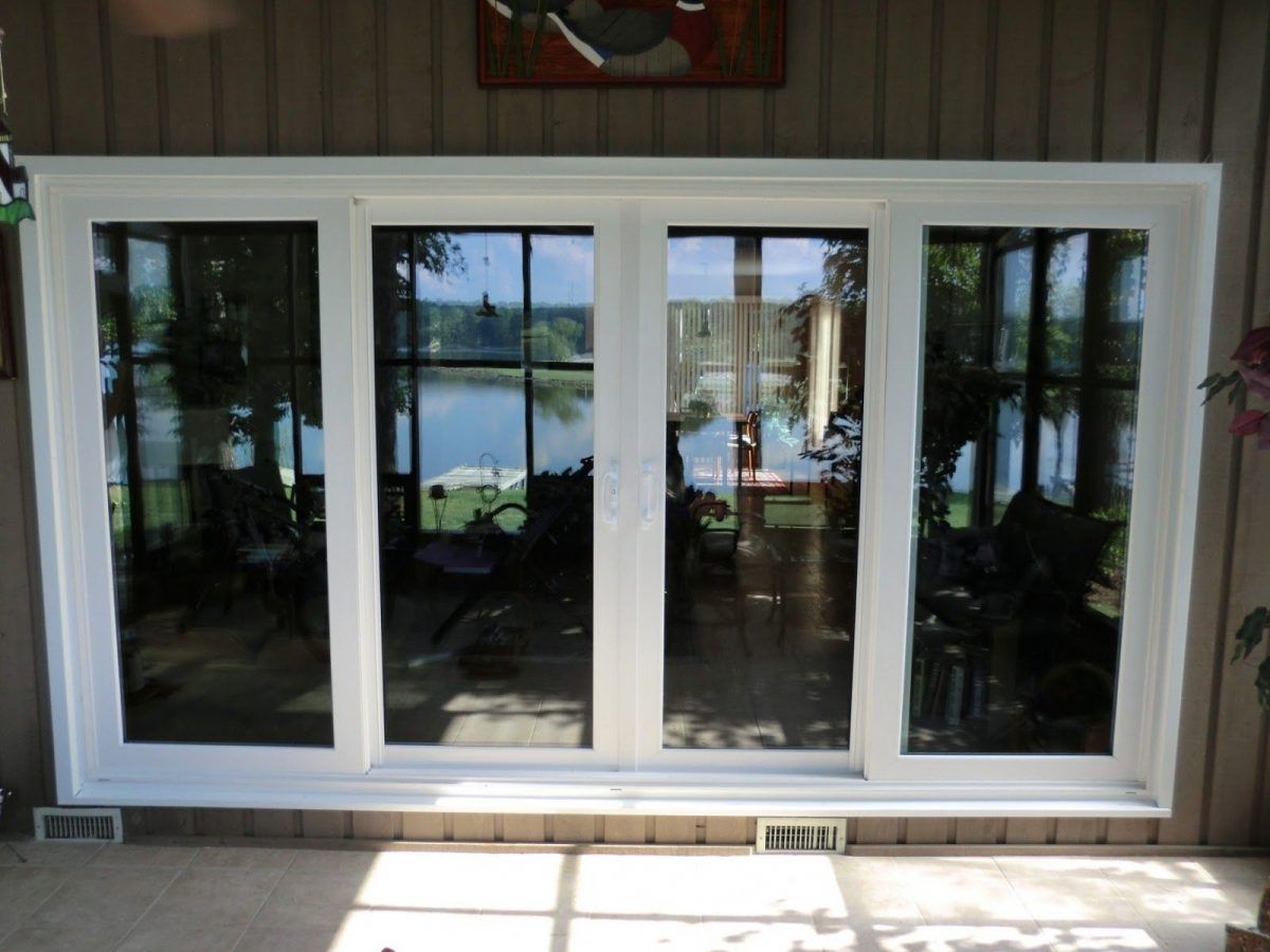 White sliding glass doors reflecting a lakeside view on a wooden exterior wall