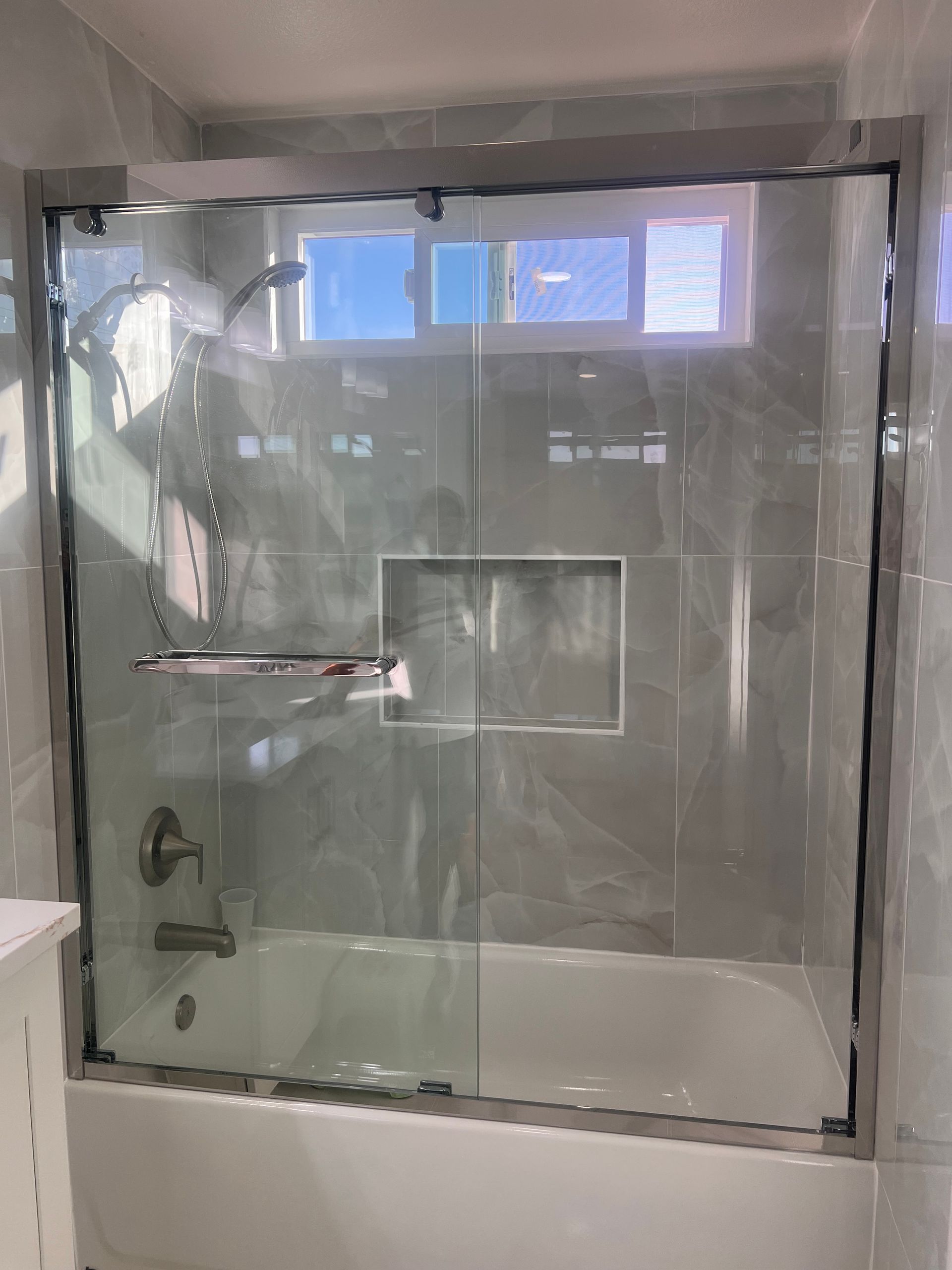 Glass shower enclosure with frosted panels, chrome handle, and tiled bathroom wall