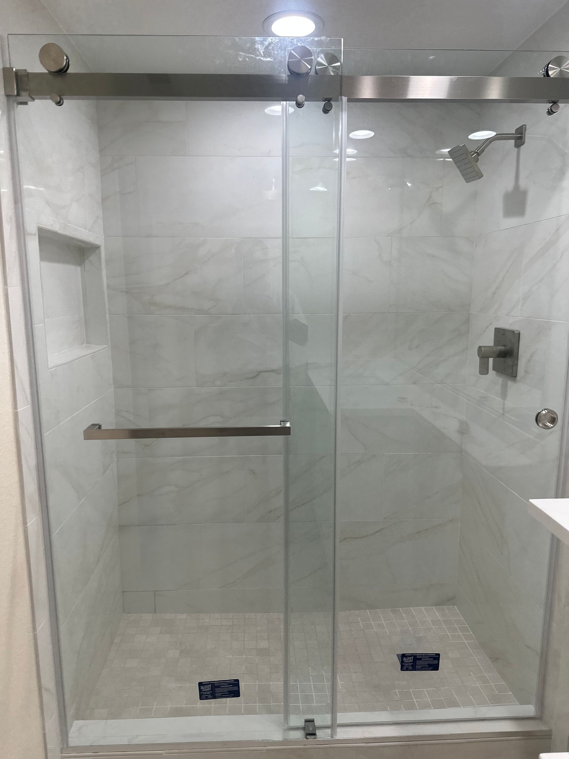 Glass shower enclosure with chrome fixtures in a tiled bathroom