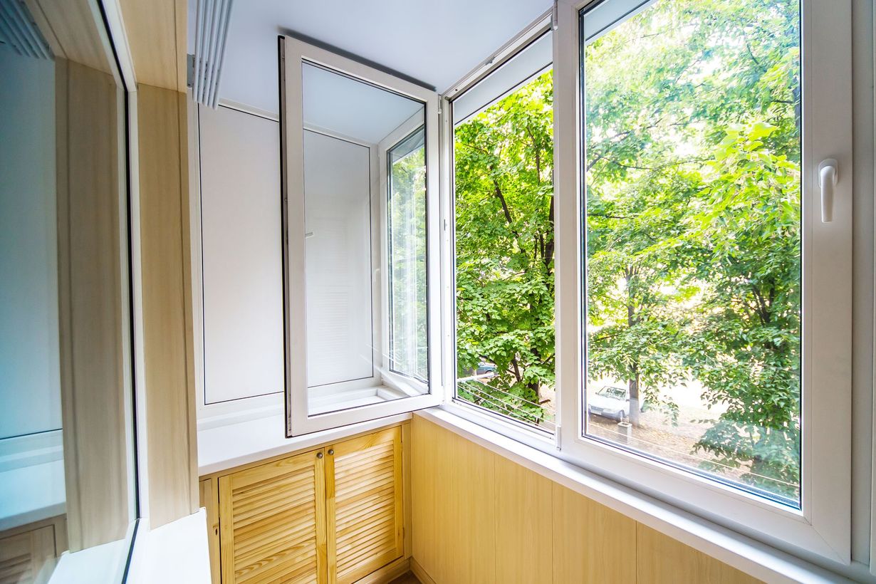 Open windows beside a yellow cabinet, with green trees visible outside.