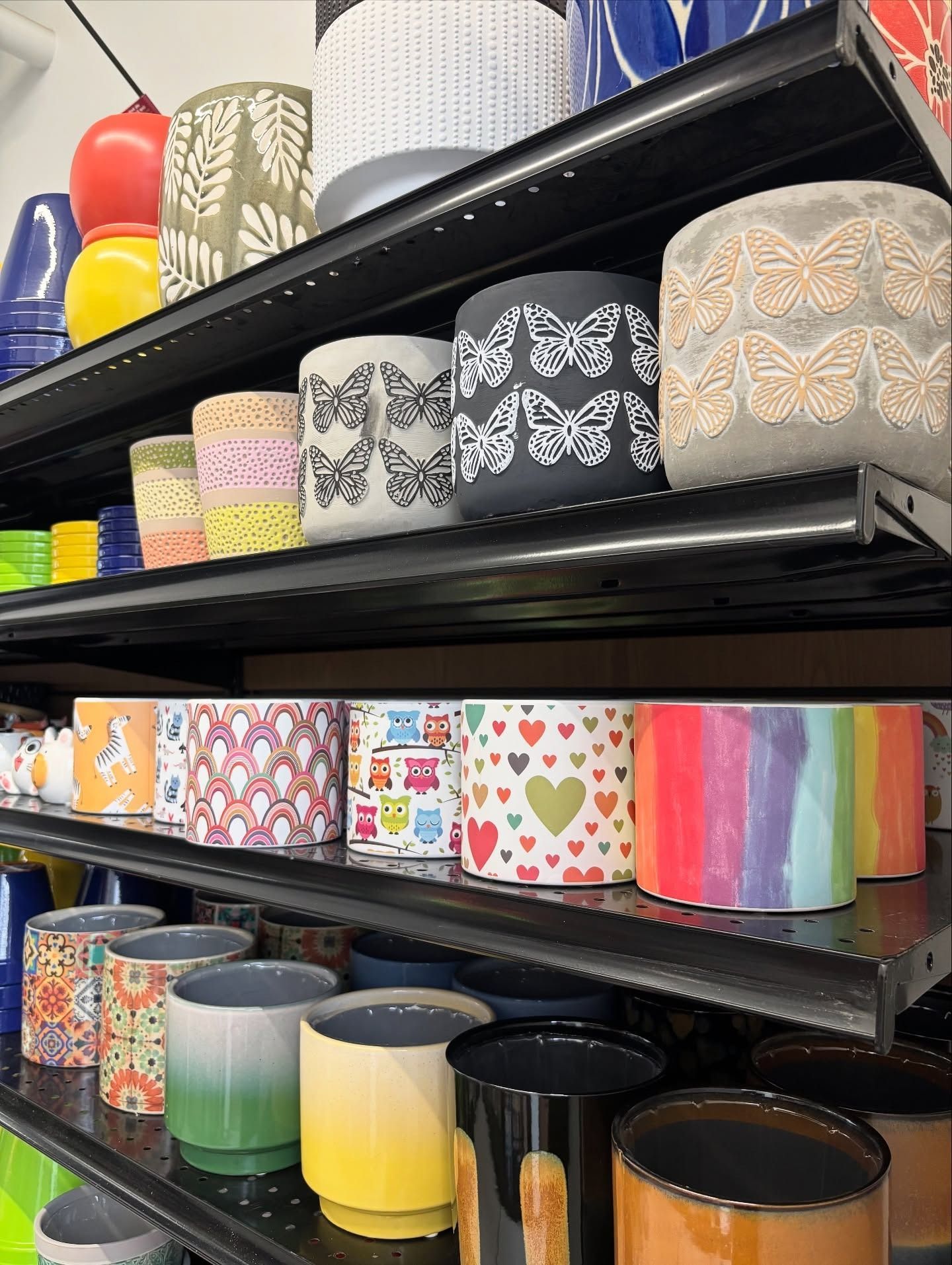 Shelves of decorative plant pots with various patterns and colors.