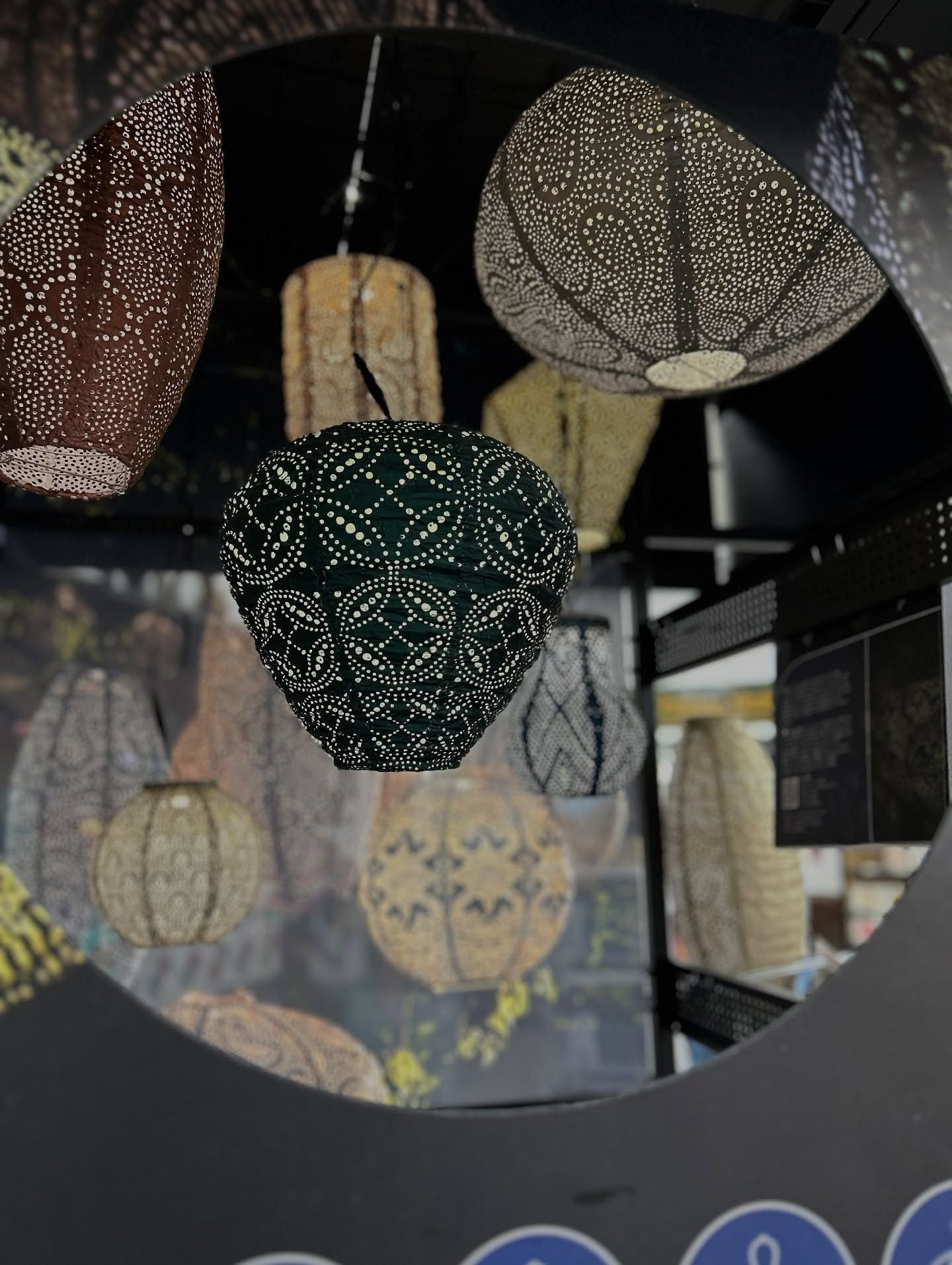 Lamps with intricate cut-out designs hang from the ceiling. Various colors: brown, green, gold.