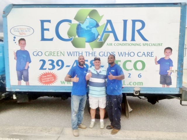 Three people posing in front of an ECOAIR company truck with a large green-and-blue logo.