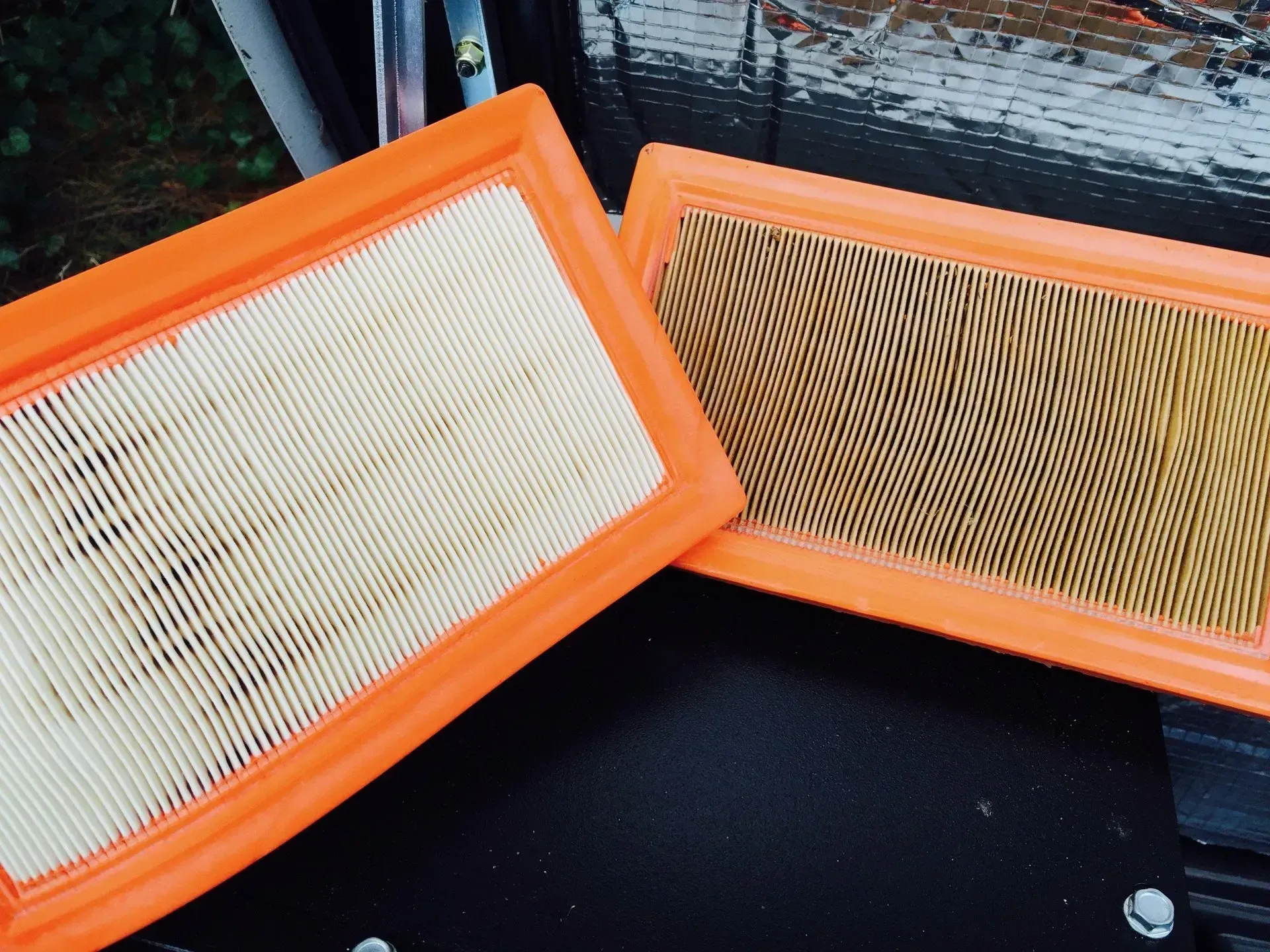 Two rectangular orange-framed air filters; one clean, the other dirty.