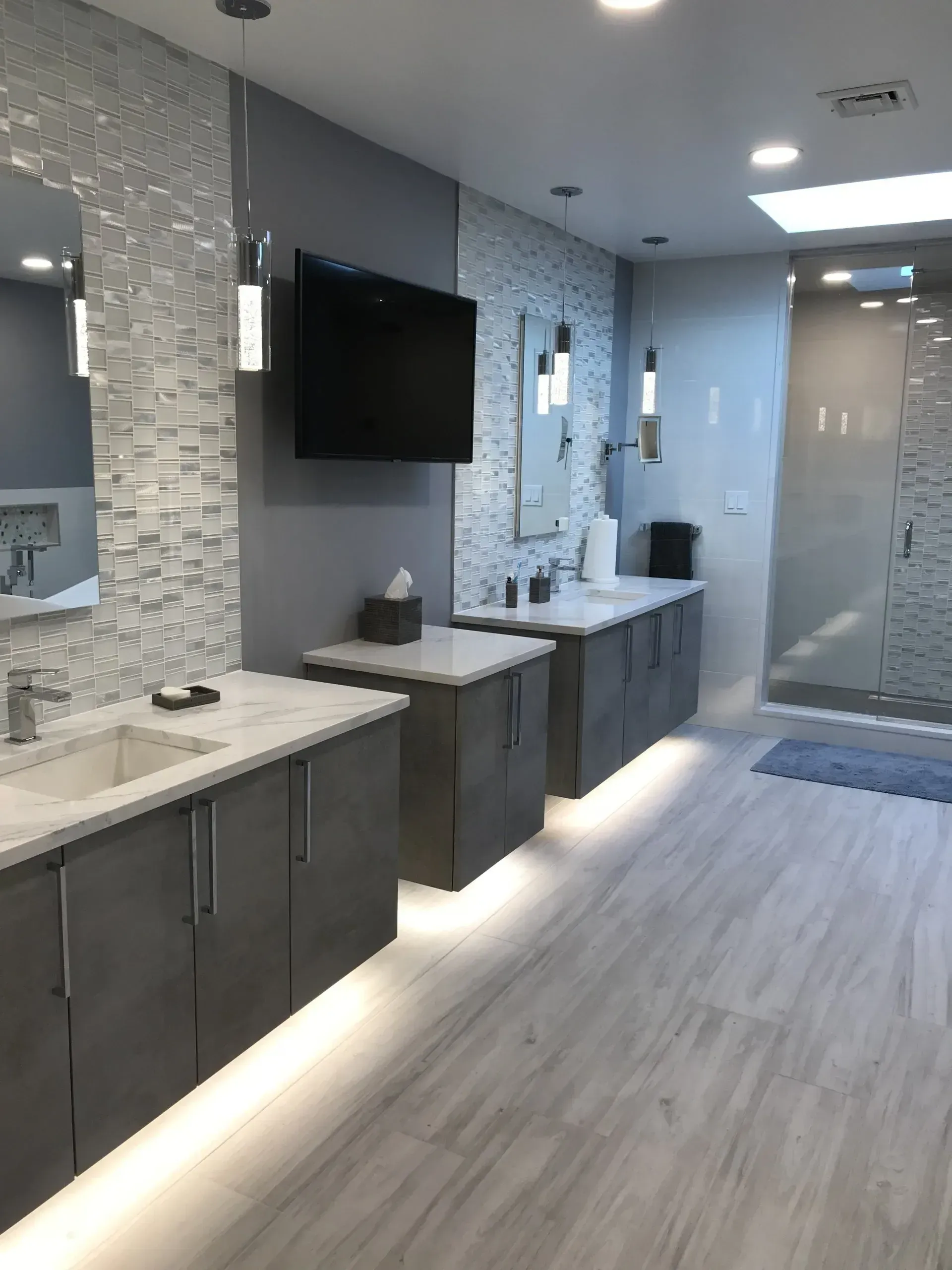 Modern bathroom with gray vanities, tile accents, and a large shower.
