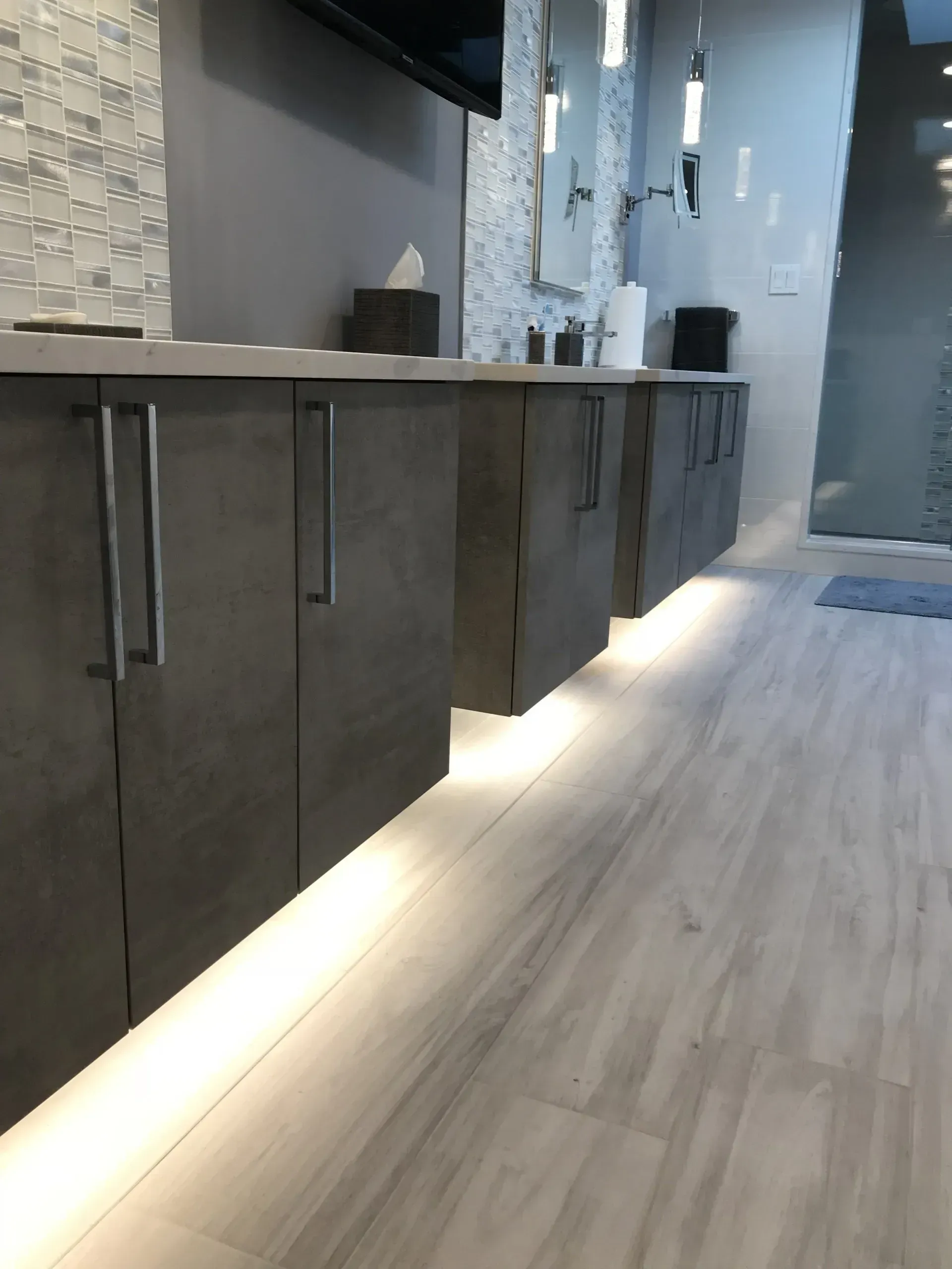 Gray cabinets with under-cabinet lighting in a modern bathroom.