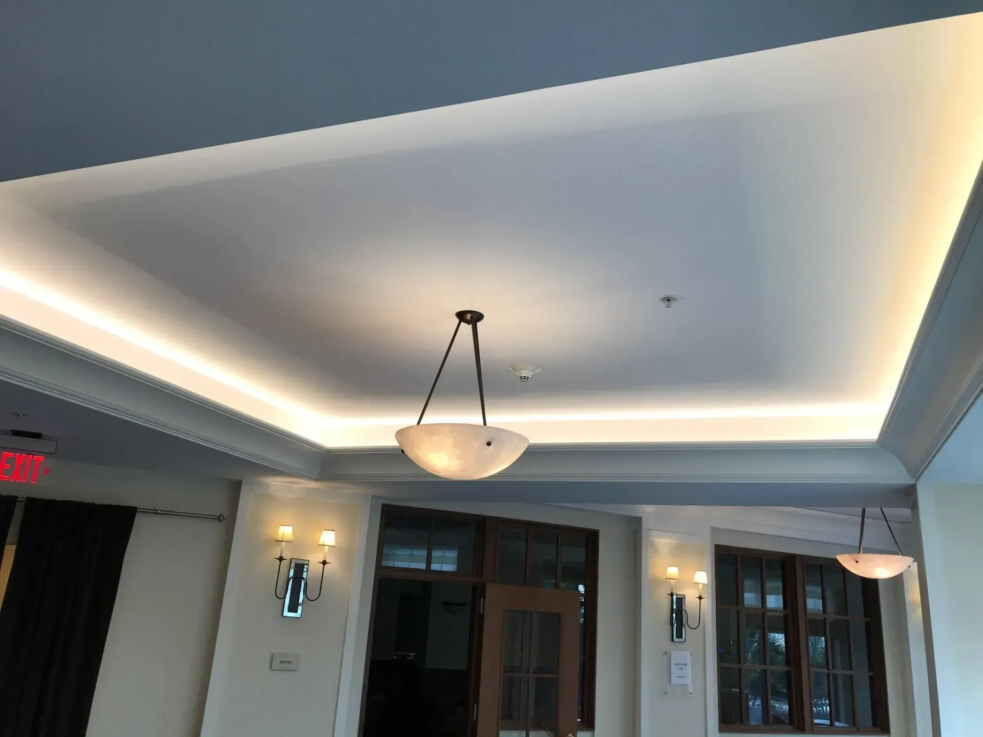 Ceiling with recessed lighting, crown molding, and hanging pendant light. Wall sconces and windows below.