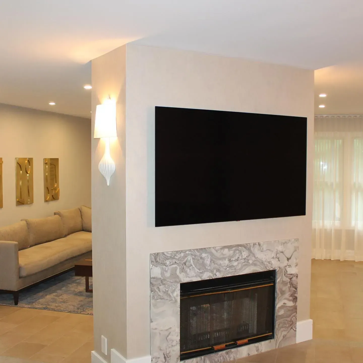 Modern living room with fireplace and television on a marble-trimmed partition wall.