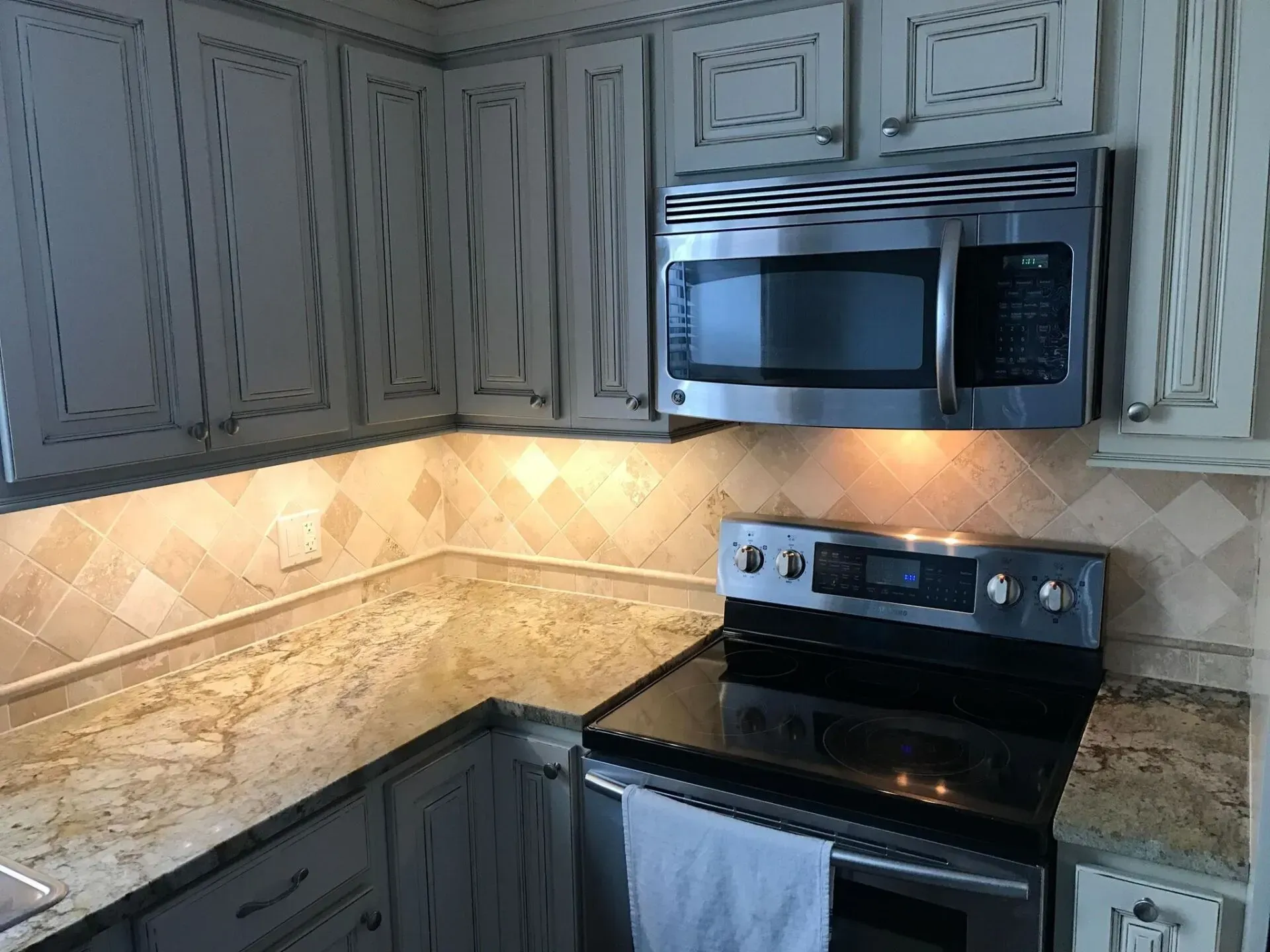 Kitchen with off-white cabinets, stainless steel appliances, granite countertops, and tiled backsplash.