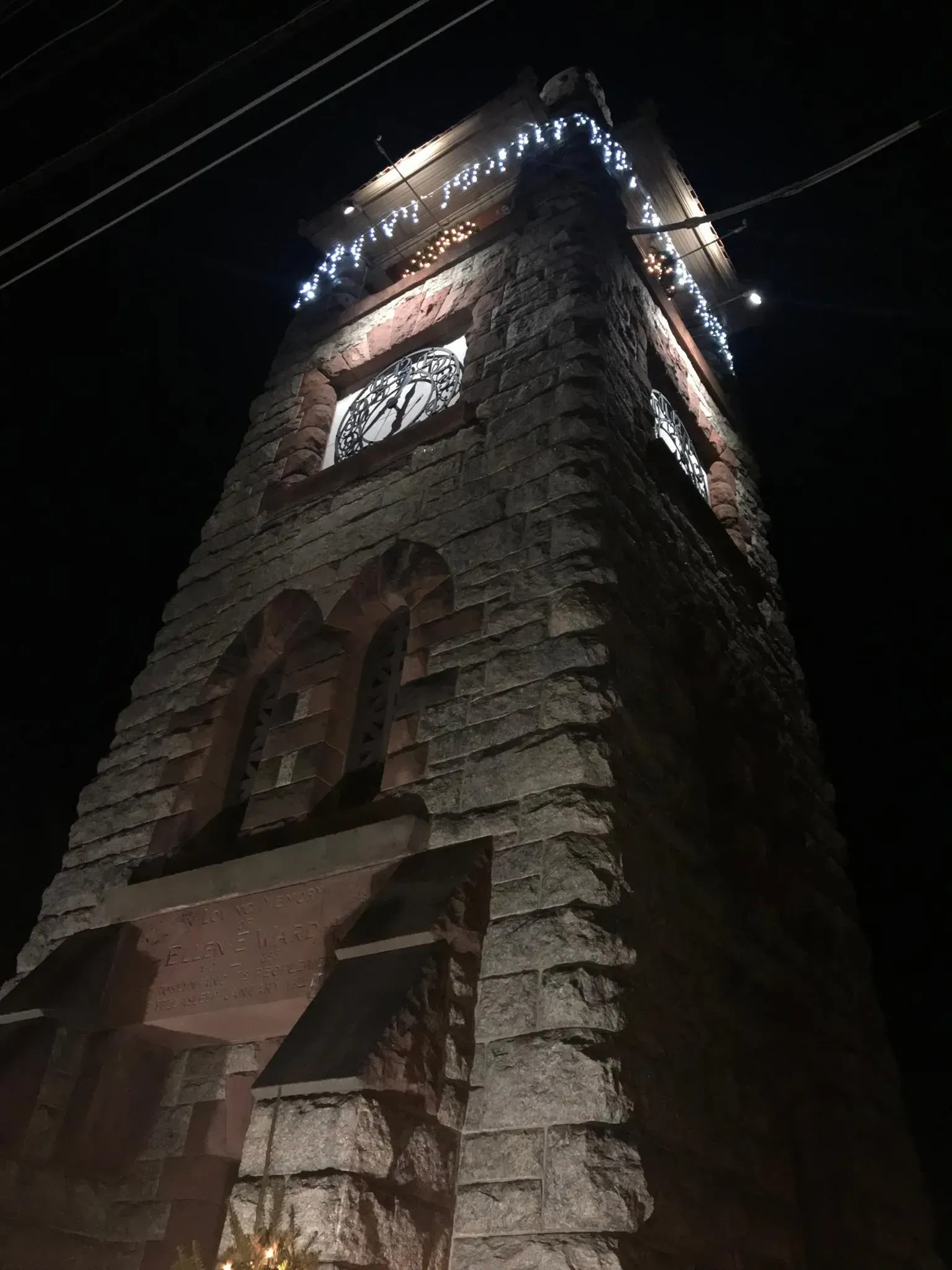Stone tower at night, illuminated by string lights.