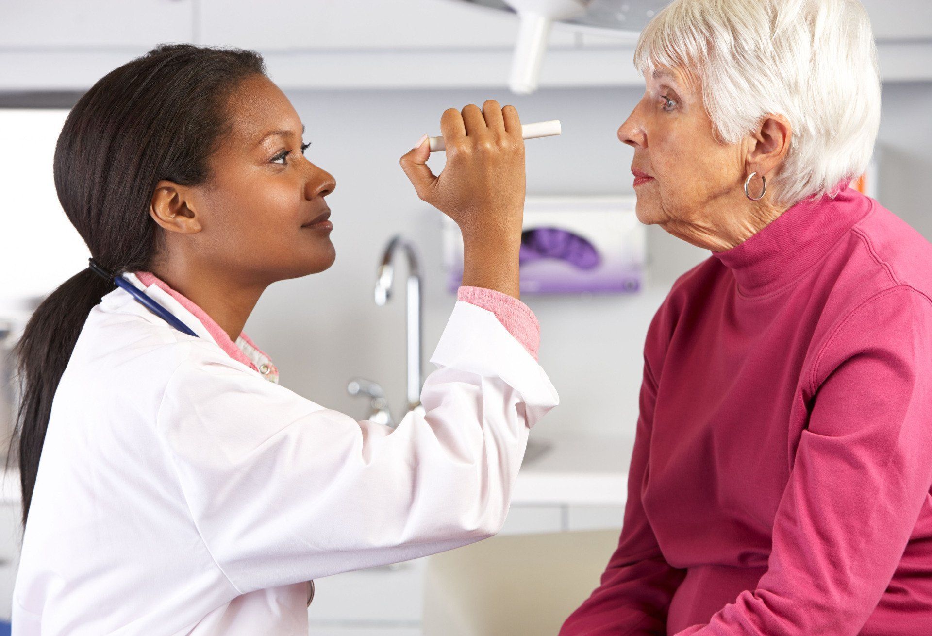 Doctor examining patient's eye with a light in a medical office.