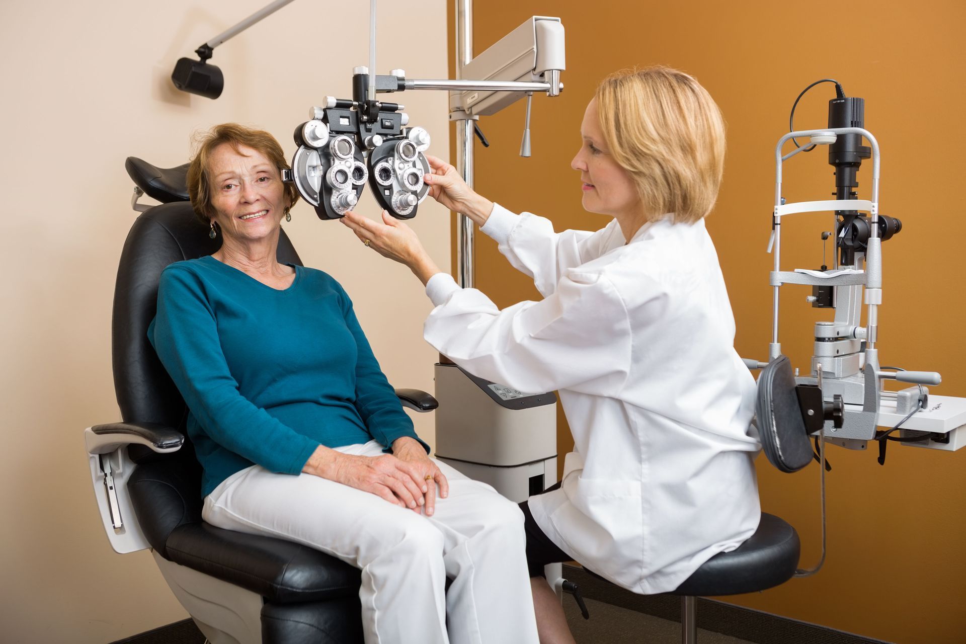 Woman receiving an eye exam; optometrist using a phoropter in an exam room.