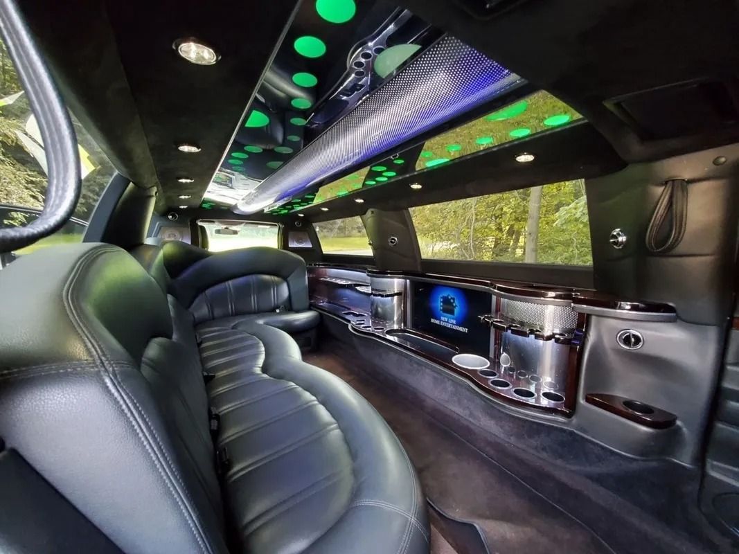 Interior of a black limousine with leather seating, mirrored ceiling, and bar area.