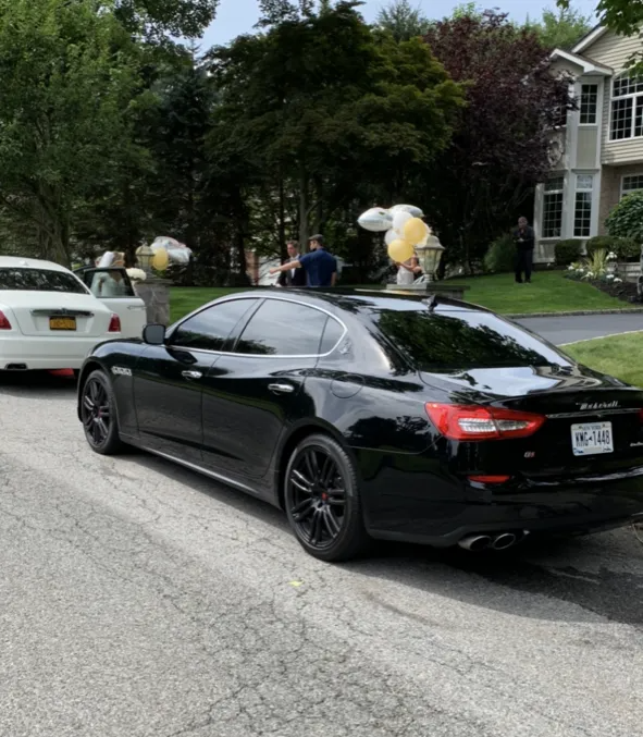 Black Maserati sedan parked on a residential street; balloons on top.