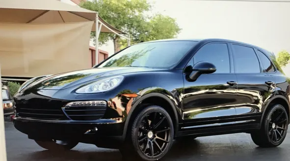 Black Porsche Cayenne SUV with black rims parked outdoors.