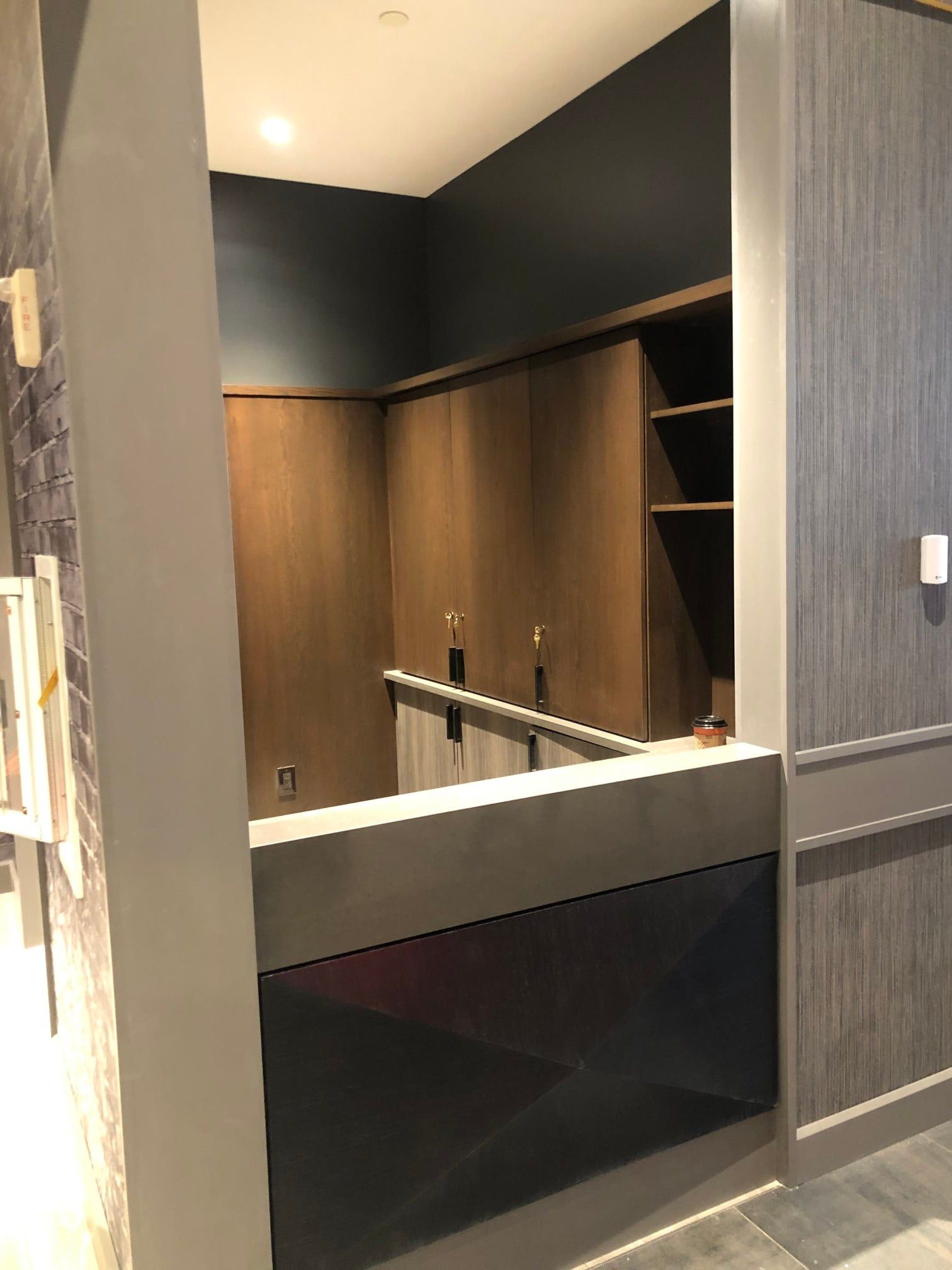 Interior bar area with dark wood cabinets, black counter, and metal taps.