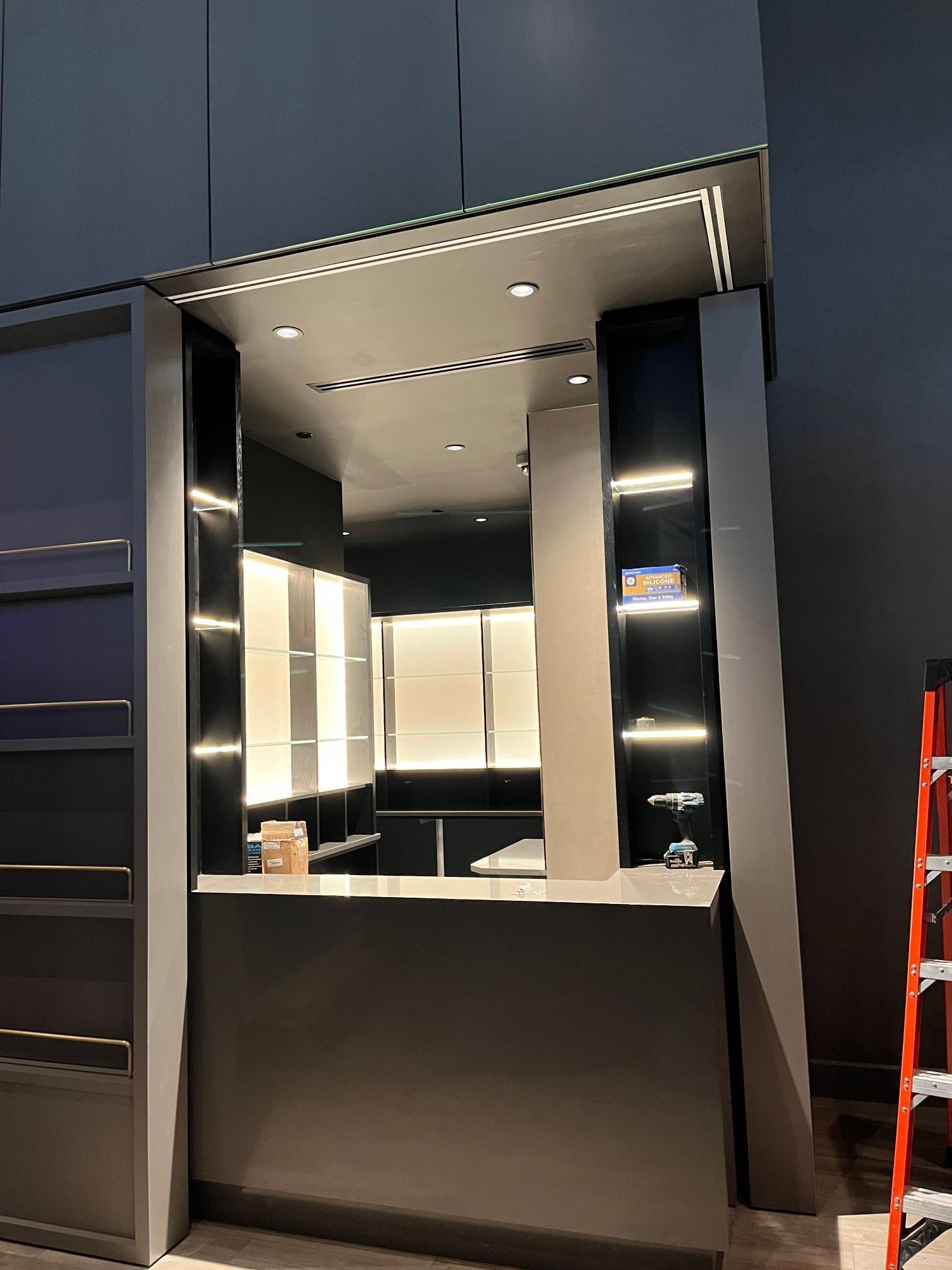 Modern retail display with shelves, overhead lighting, and angled supports; gray and black tones.