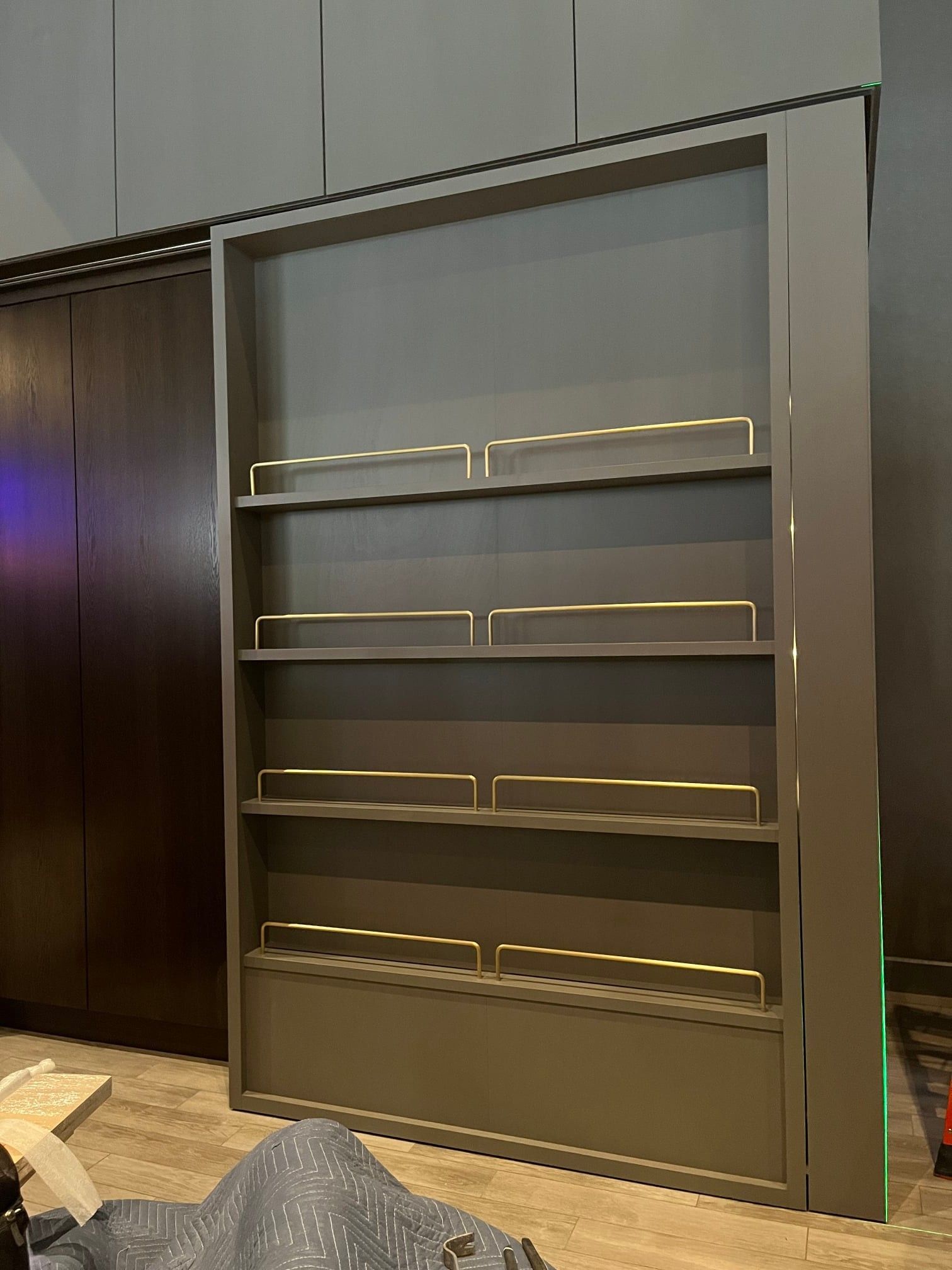 Gray shelving unit with gold accents, set against a dark wall.