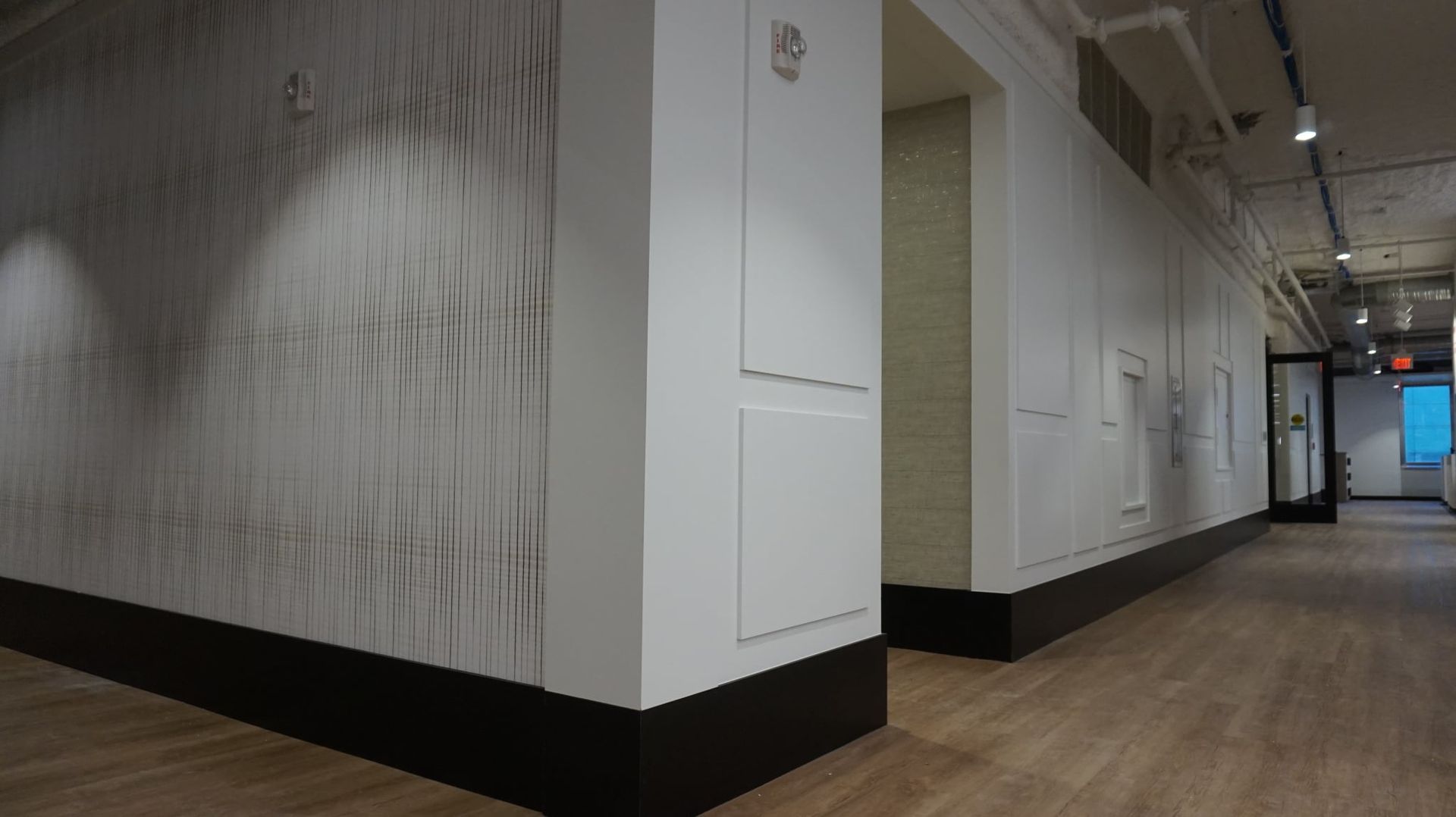 Gallery with white walls, dark baseboards, and wooden floors. Artwork visible.