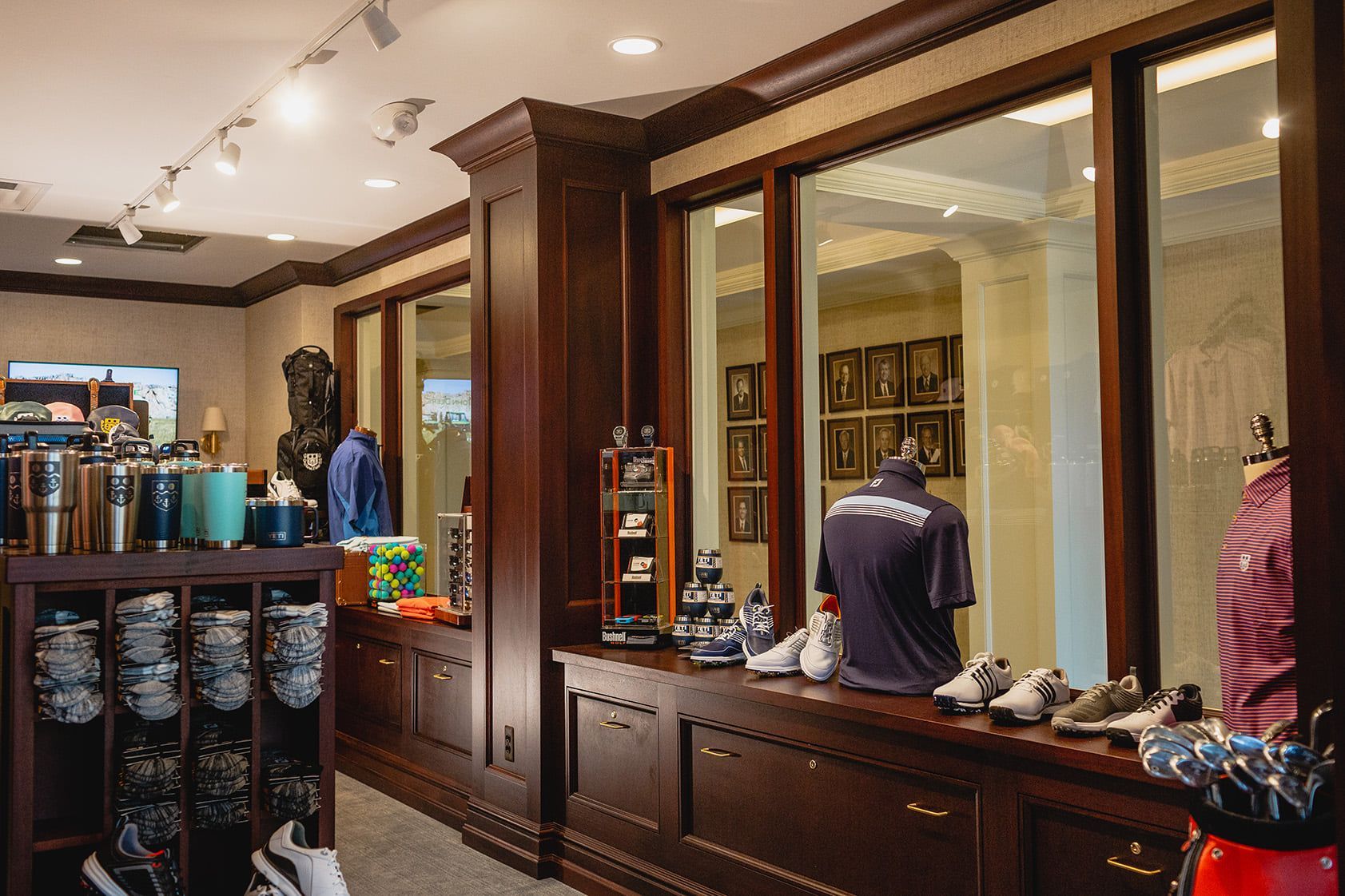 Golf shop interior with wood paneling, displays of golf apparel, shoes, and accessories.