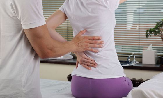 A man is giving a woman a massage on her back.