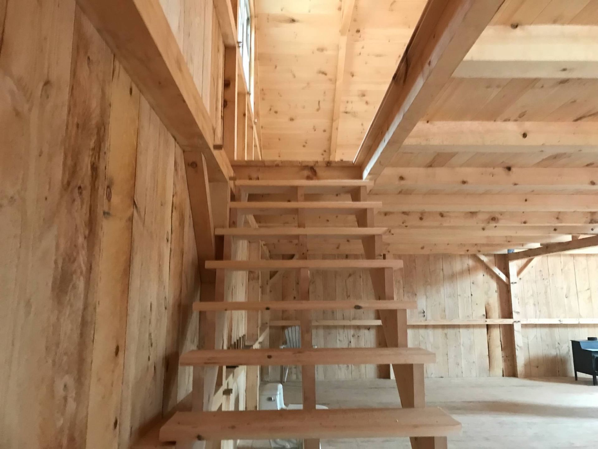 Wooden staircase in a light-colored wooden interior, leading to a loft.