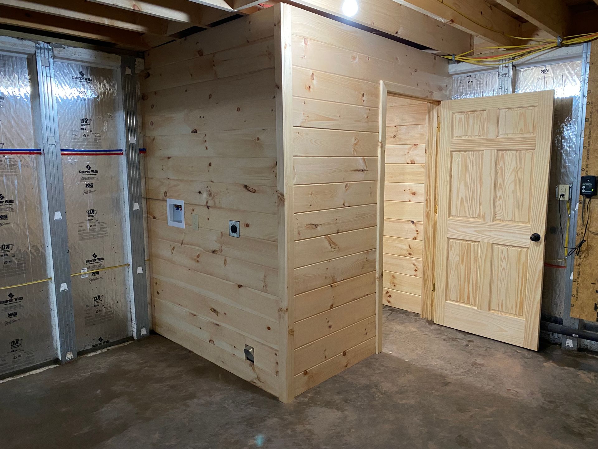 Basement room with wooden walls and door. Insulation on surrounding walls.