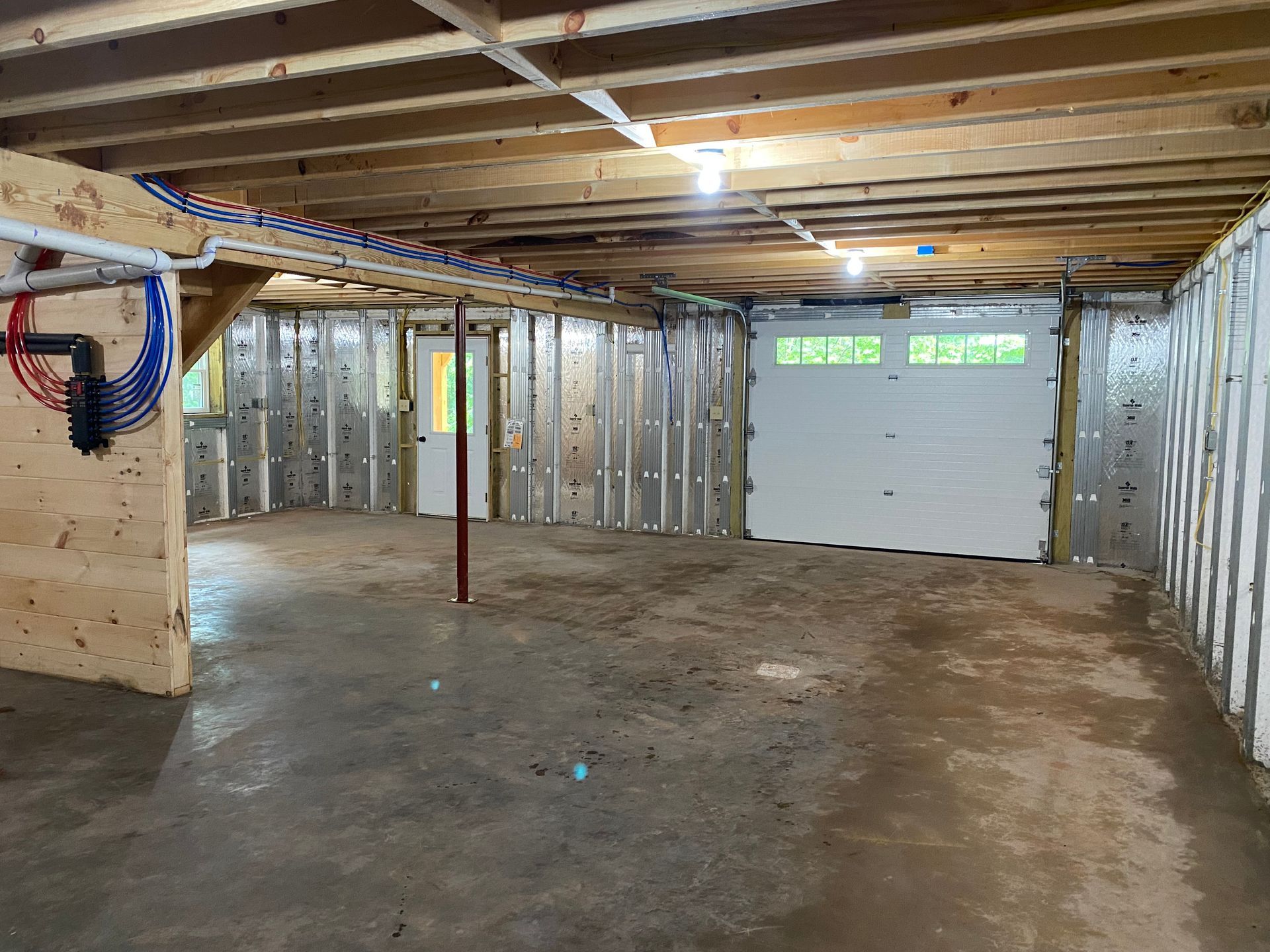 Empty garage interior with a concrete floor, garage door, and exposed framing.