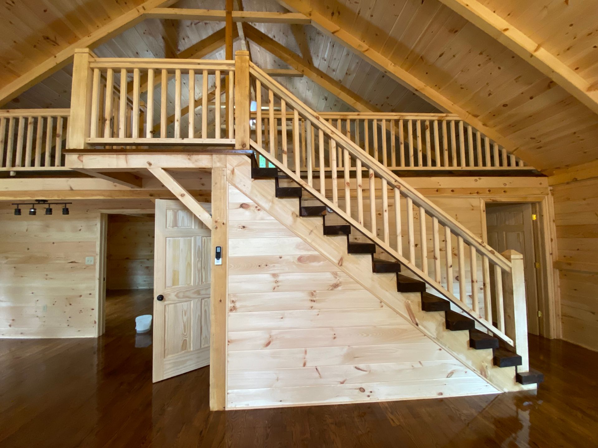 Interior view of a wooden cabin with a staircase leading to a loft area.