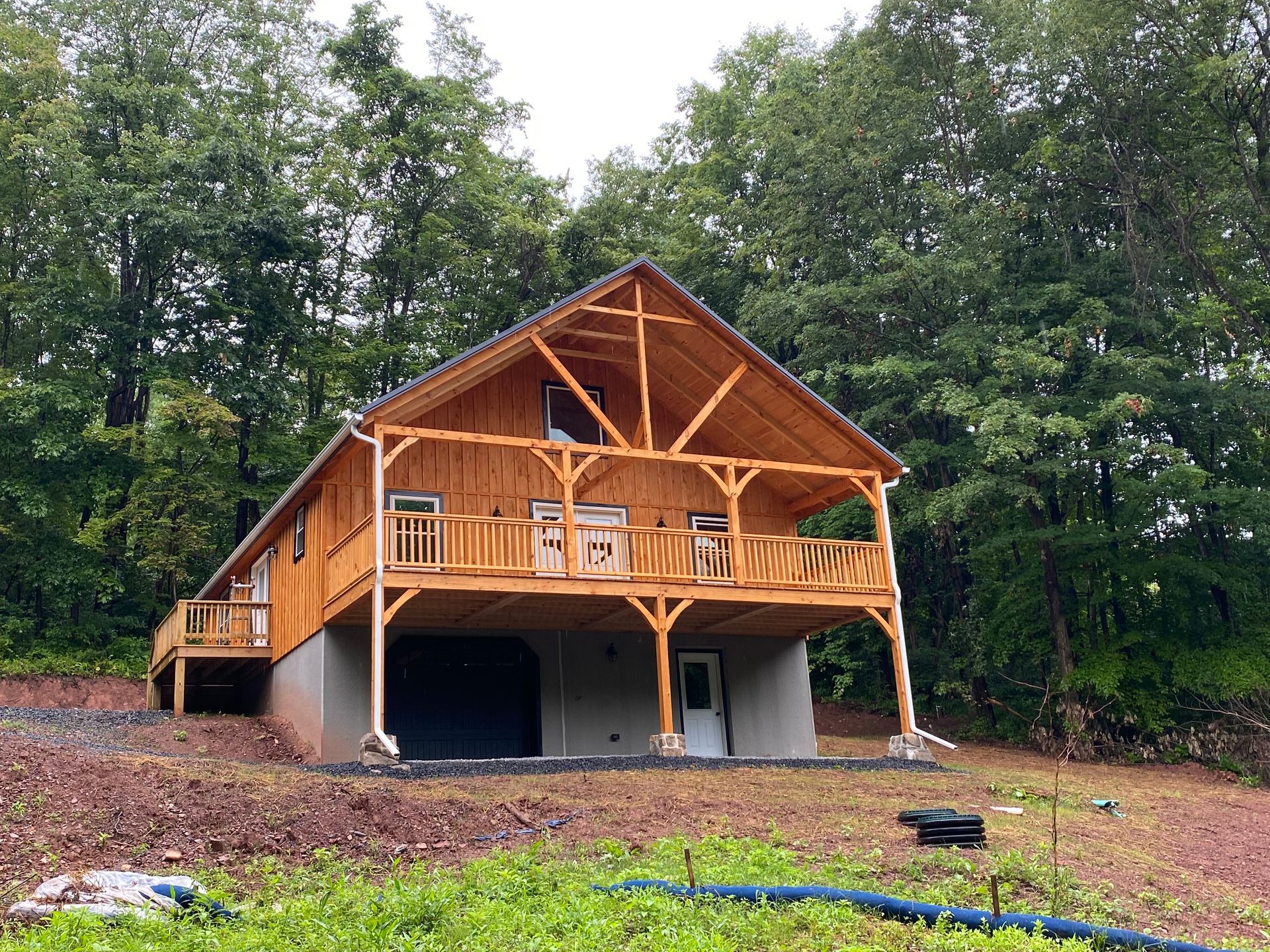Wooden cabin with a covered porch in a wooded setting.