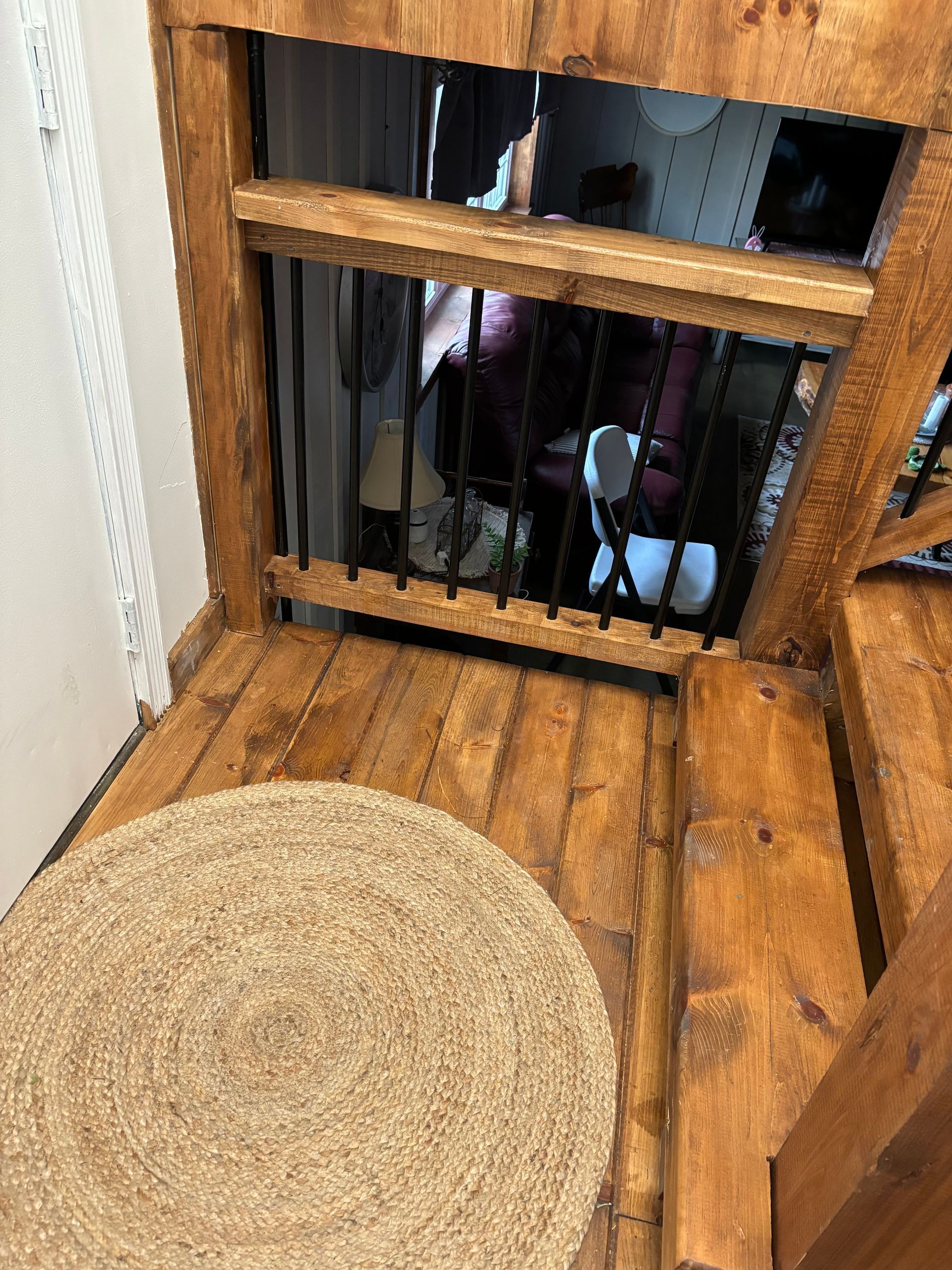 Wooden structure with a round rug, bars, and a person partially visible in the background.
