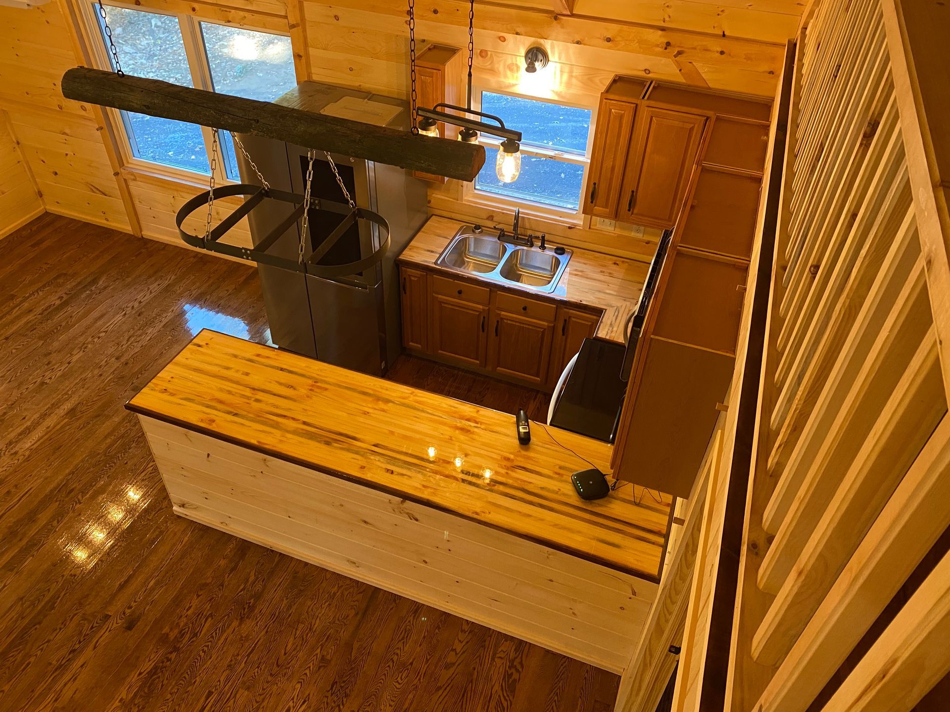 Interior view of a wooden cabin kitchen with a bar, refrigerator, and sink.