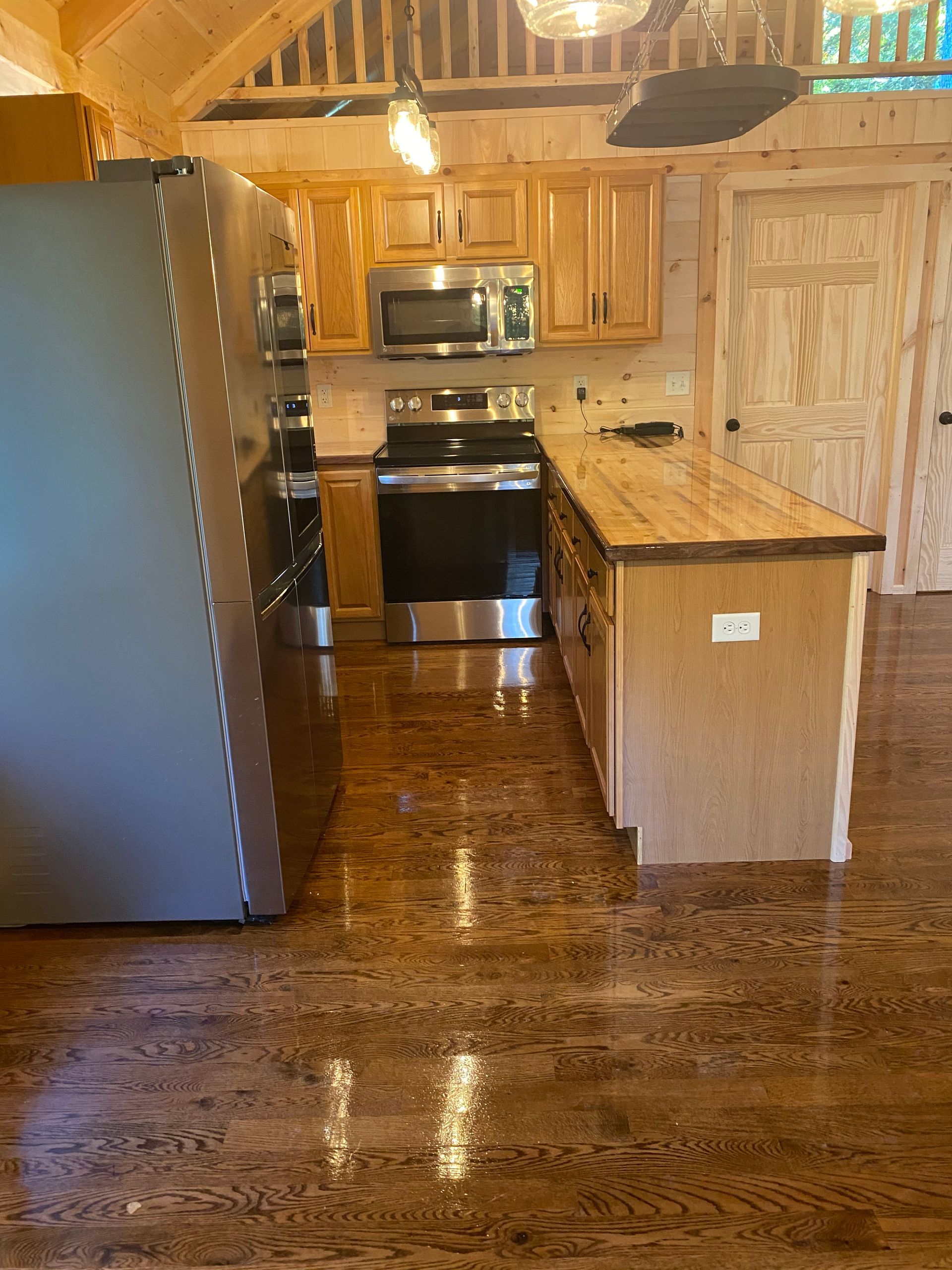 Kitchen with wooden cabinets, stainless steel appliances, and hardwood floors.