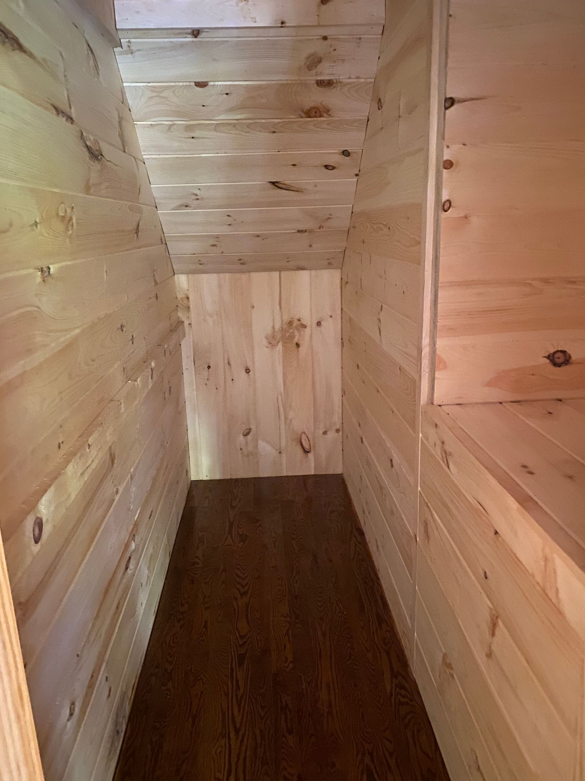 Interior of a small wooden storage space, with wooden walls, ceiling and floor.