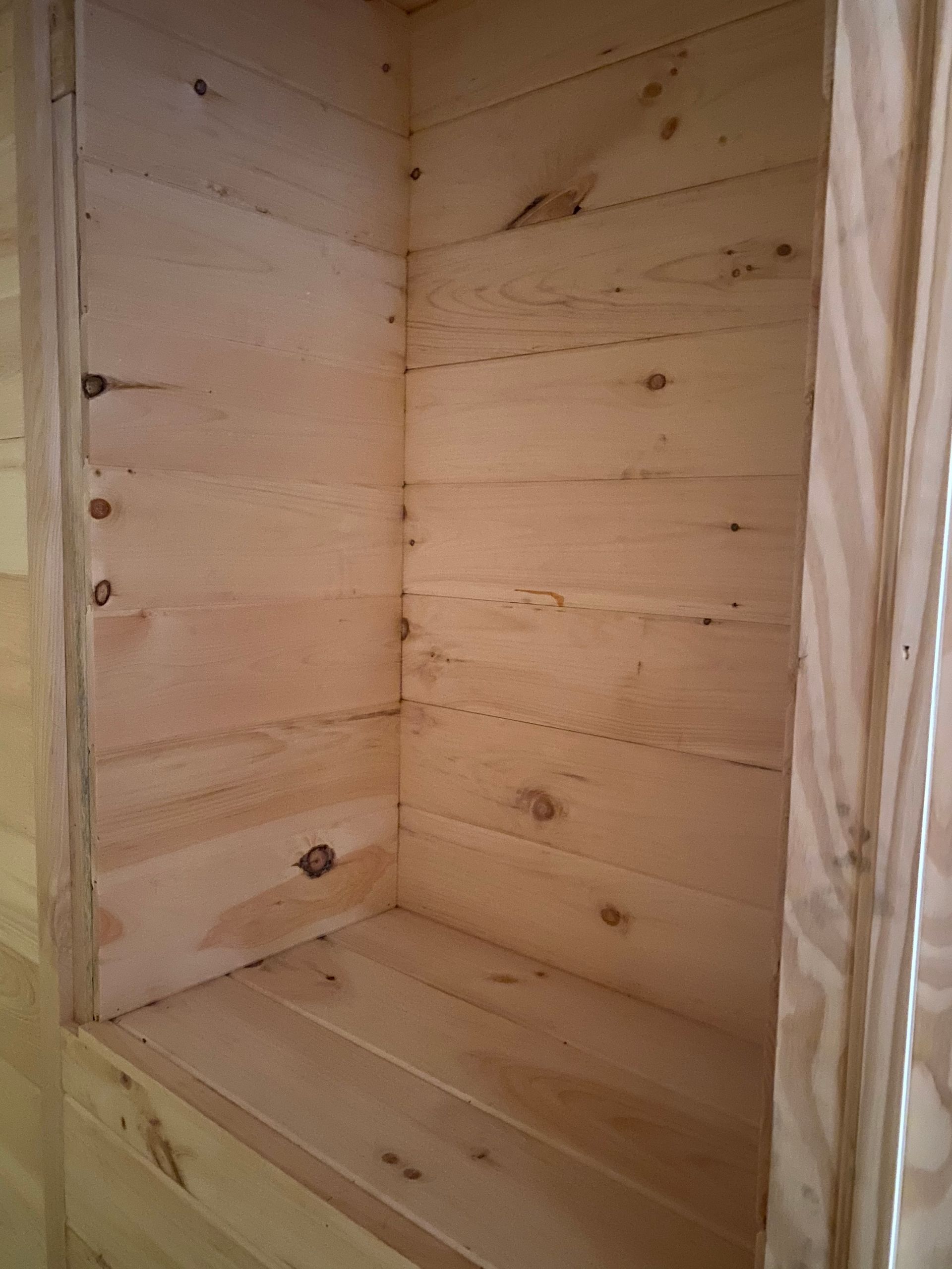 Empty wooden alcove with horizontal plank walls and base. Natural wood color.