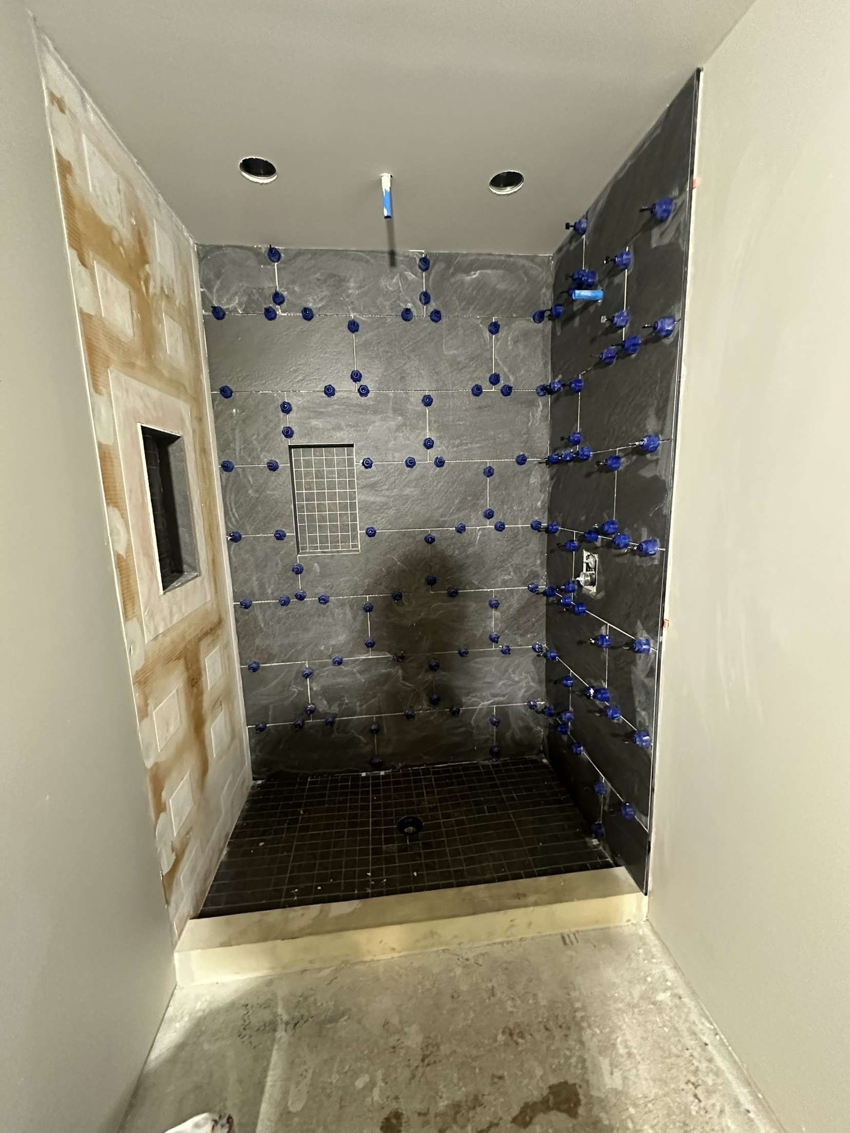 Bathroom shower under construction with tiled walls and floor.