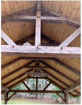 Wooden gazebo ceiling with exposed beams and light fixtures.