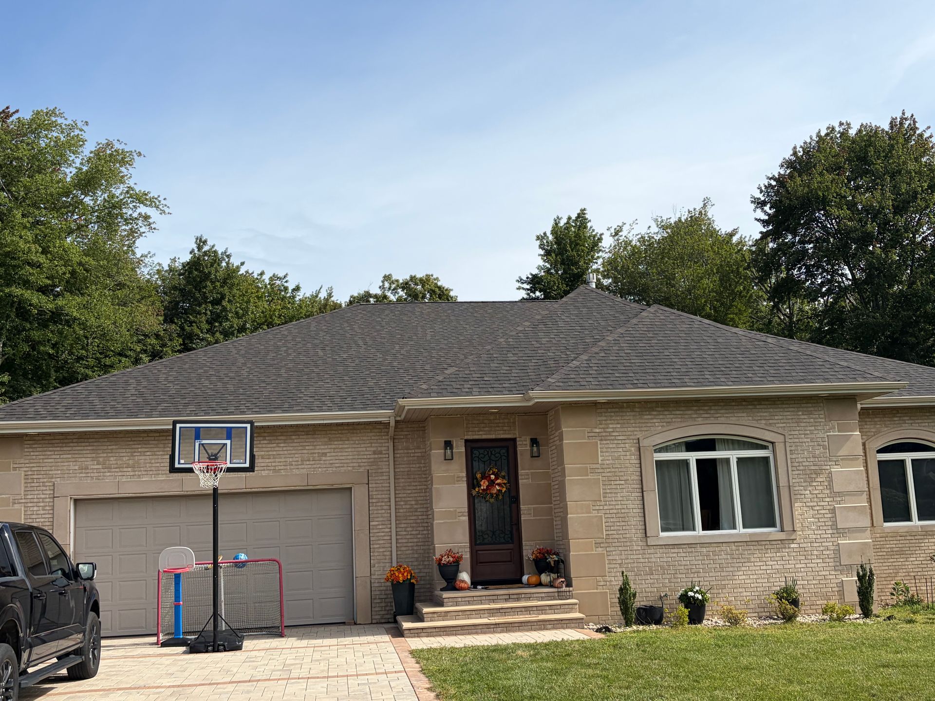 Single-story brick house with two-car garage, front porch, and basketball hoop in the driveway