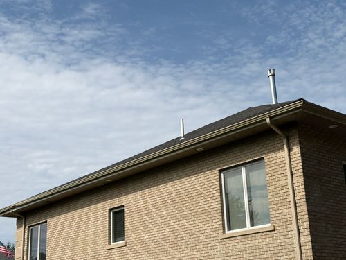 Brick house exterior with a sloped roof and a cloudy sky overhead