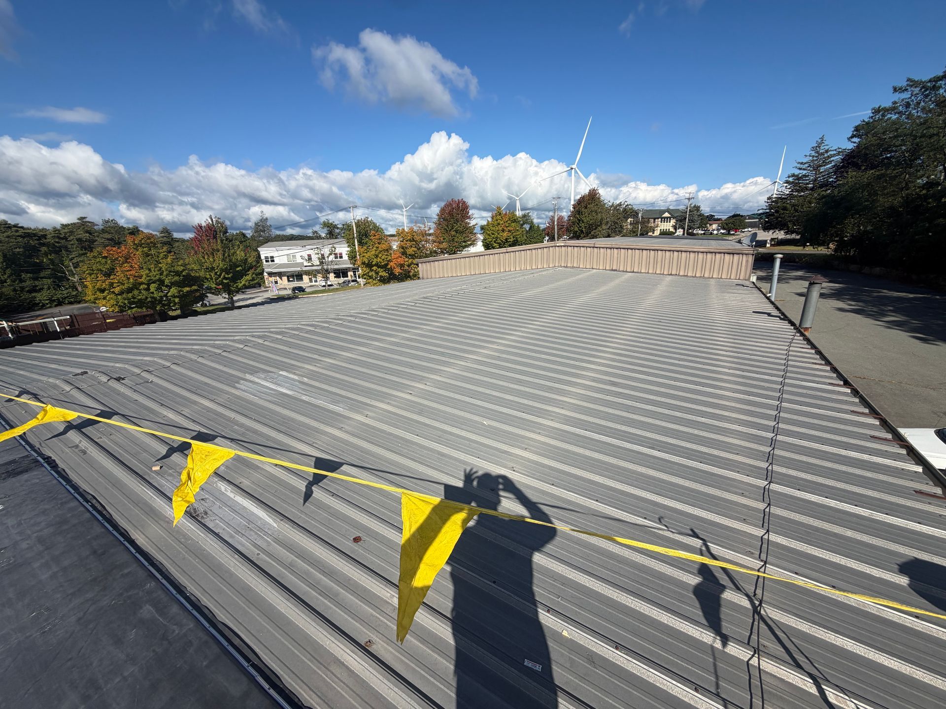 Empty rooftop deck with gray slatted surface, yellow caution tape, and a cloudy blue sky overhead