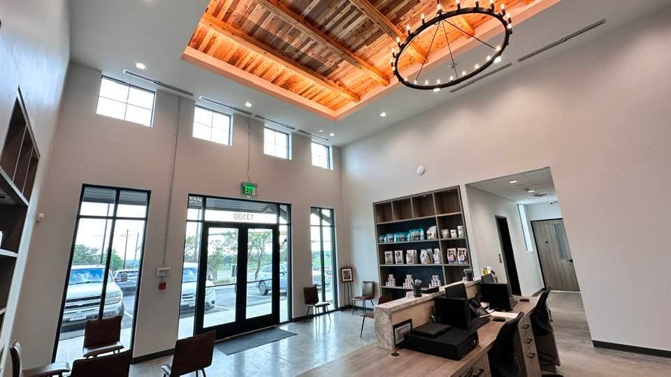 Spacious veterinary clinic reception area with high ceilings, wood accents, and a front desk.
