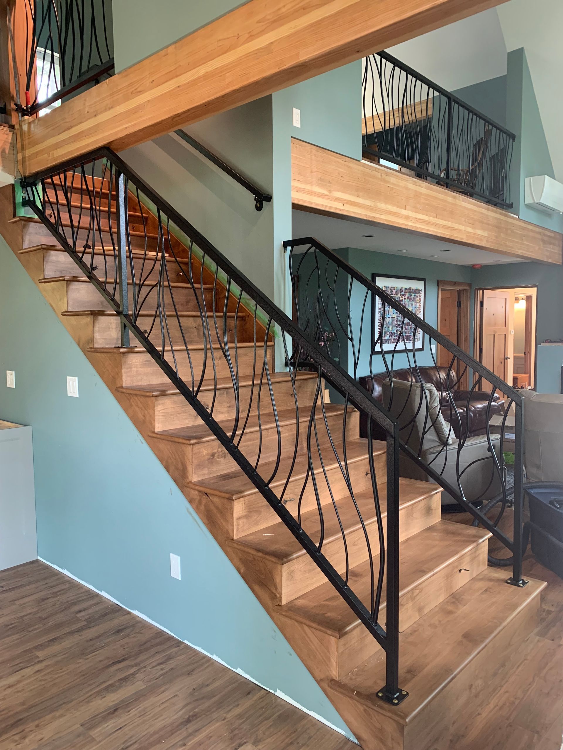 A wooden staircase with a wrought iron railing in a living room