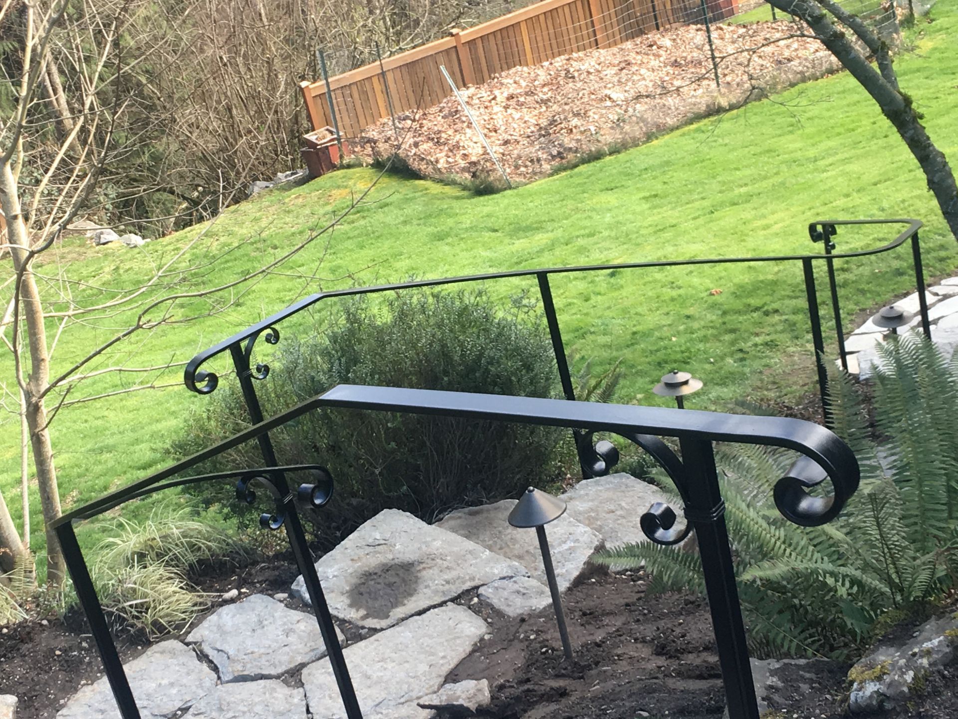 A wrought iron railing on a set of stairs leading up to a grassy hillside