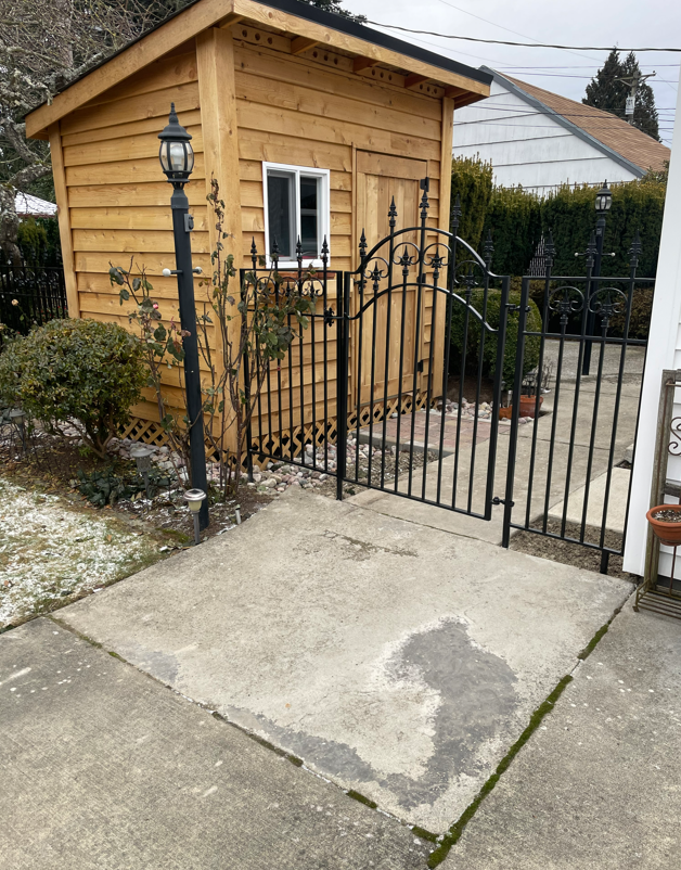 A black metal fence surrounds a garden in front of a house