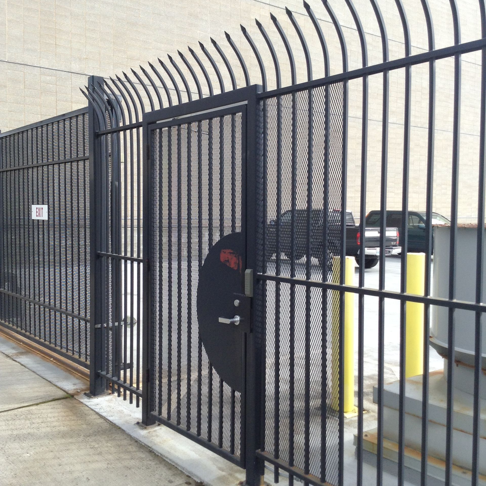 A black gate is sitting in front of a white house