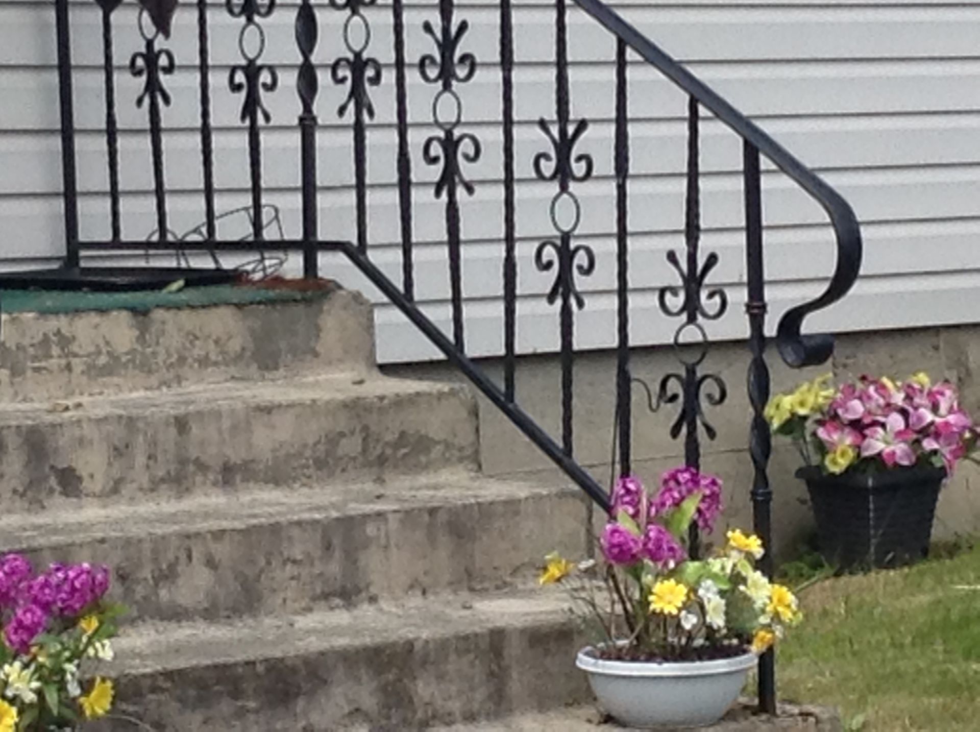 A staircase with a wrought iron railing and potted flowers