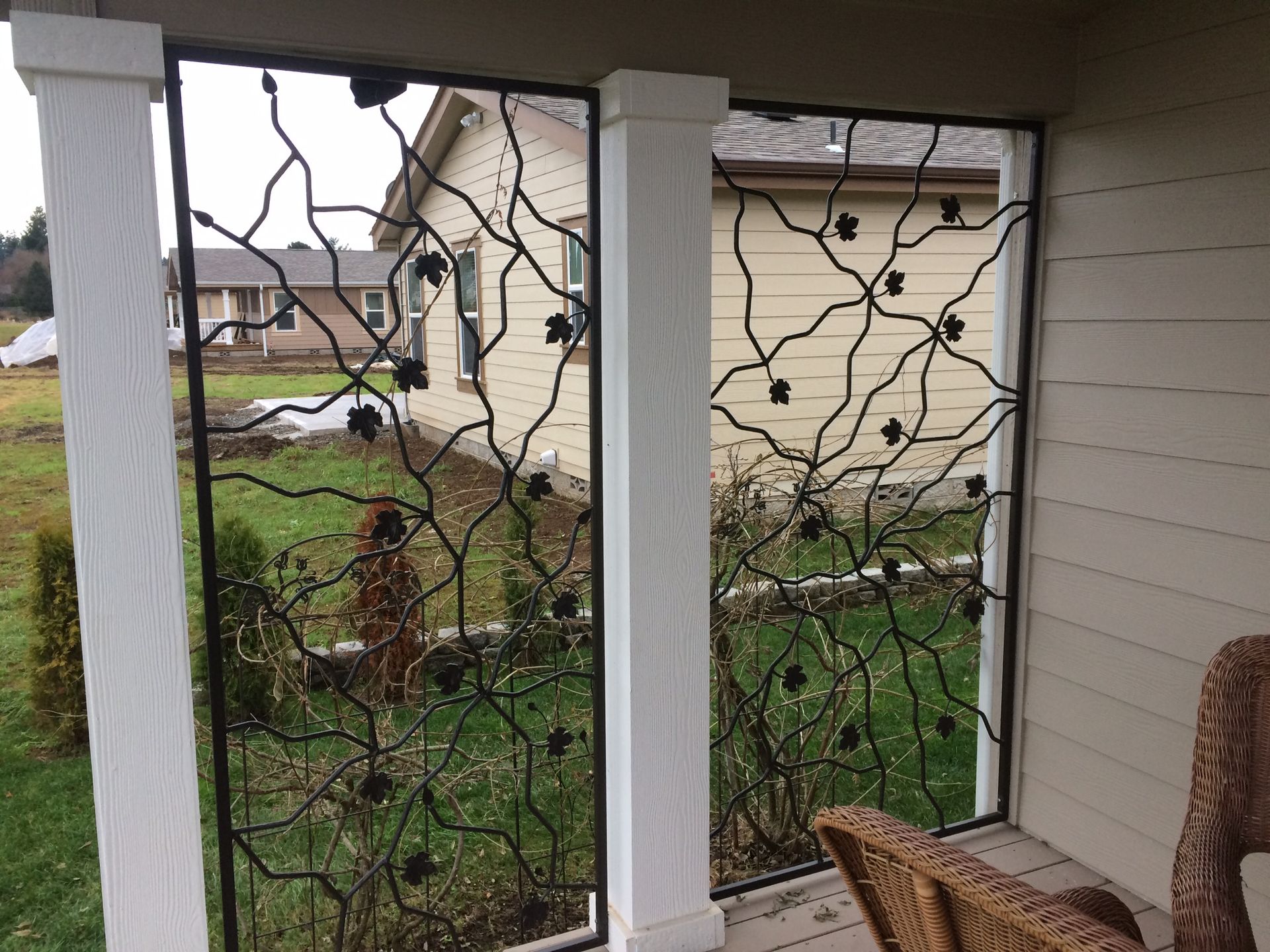 A porch with ornamental iron art and a chair