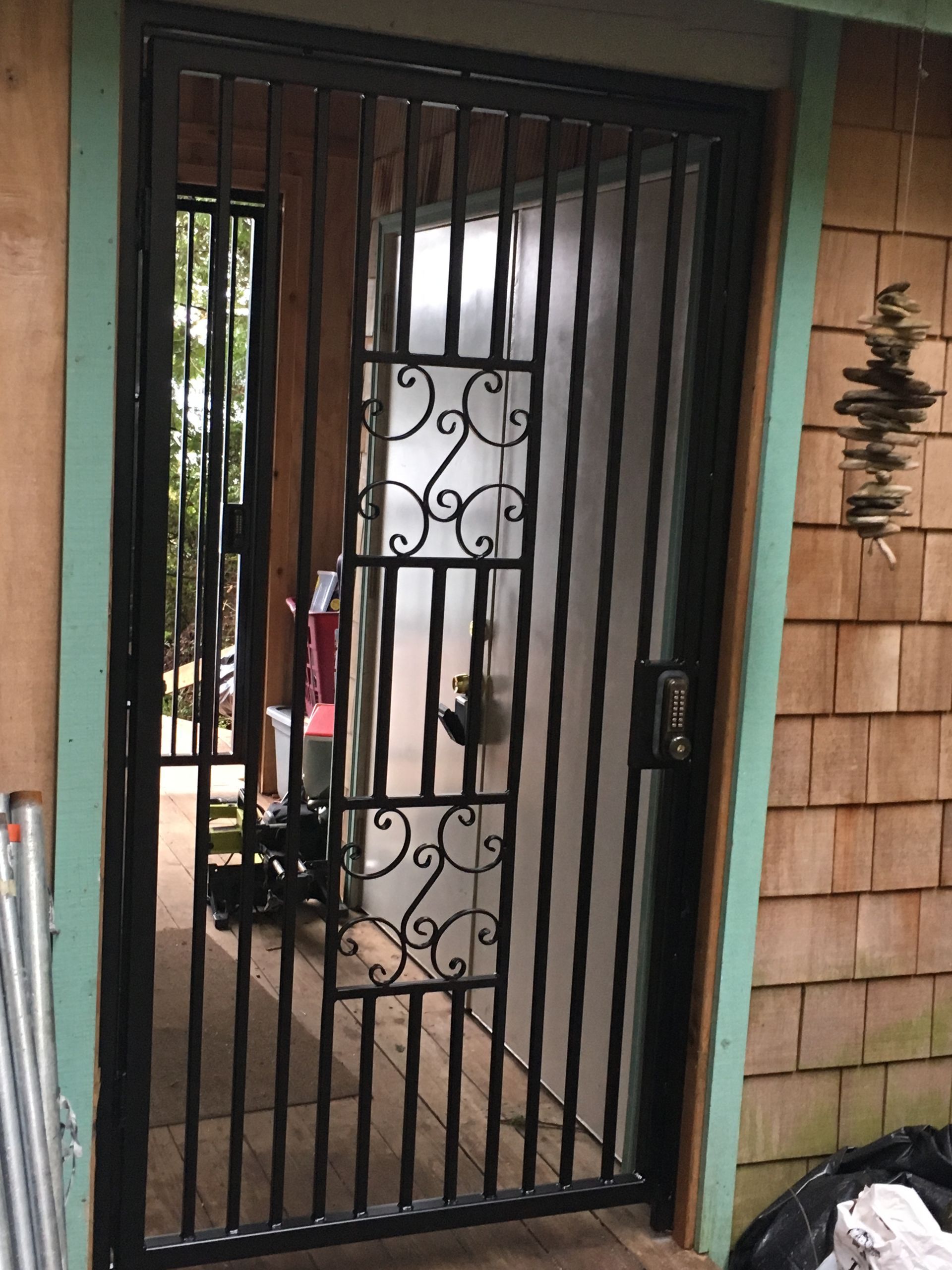 A black wrought iron gate is sitting in front of a door