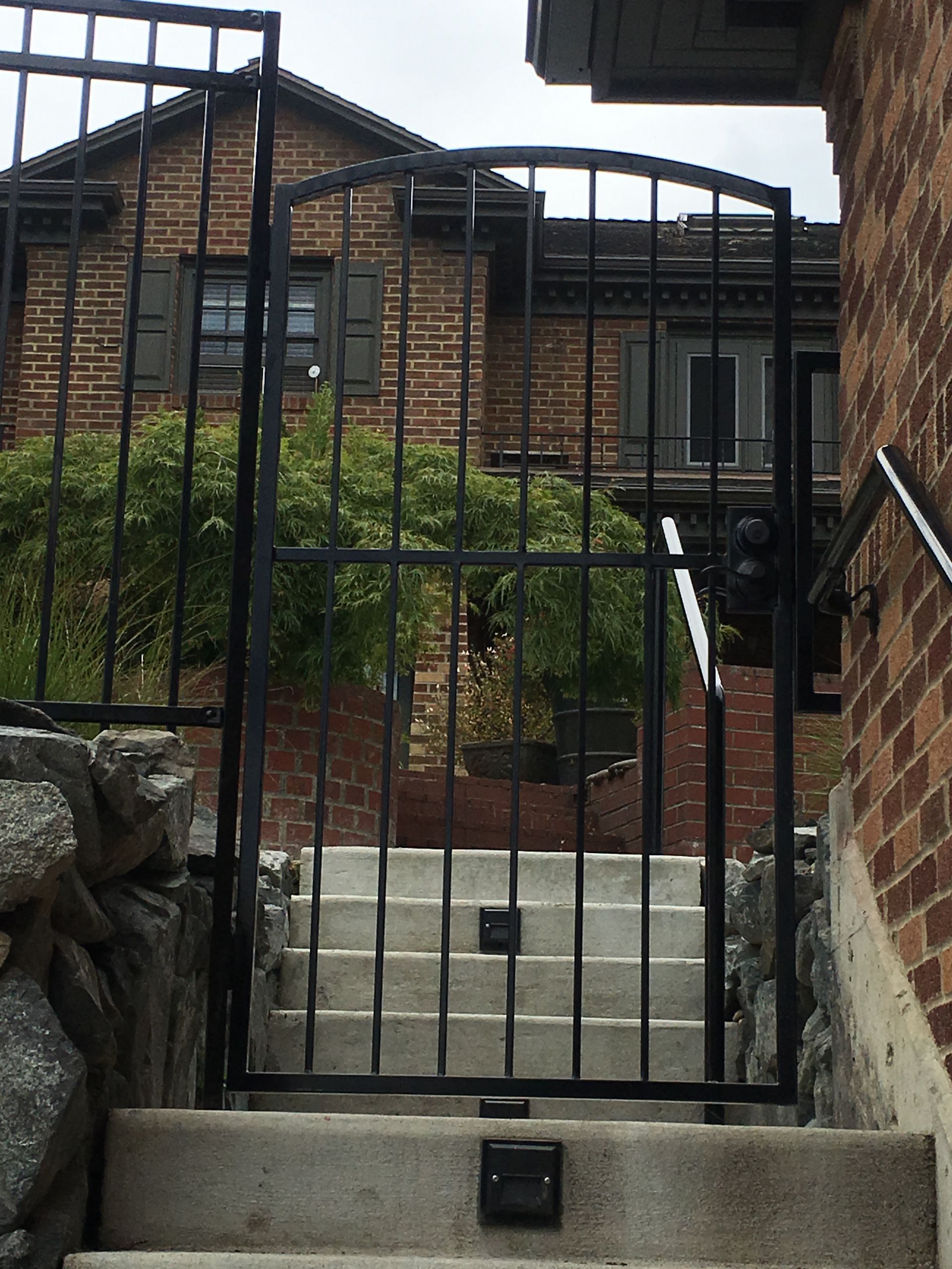 Stairs leading up to a brick house with a black gate