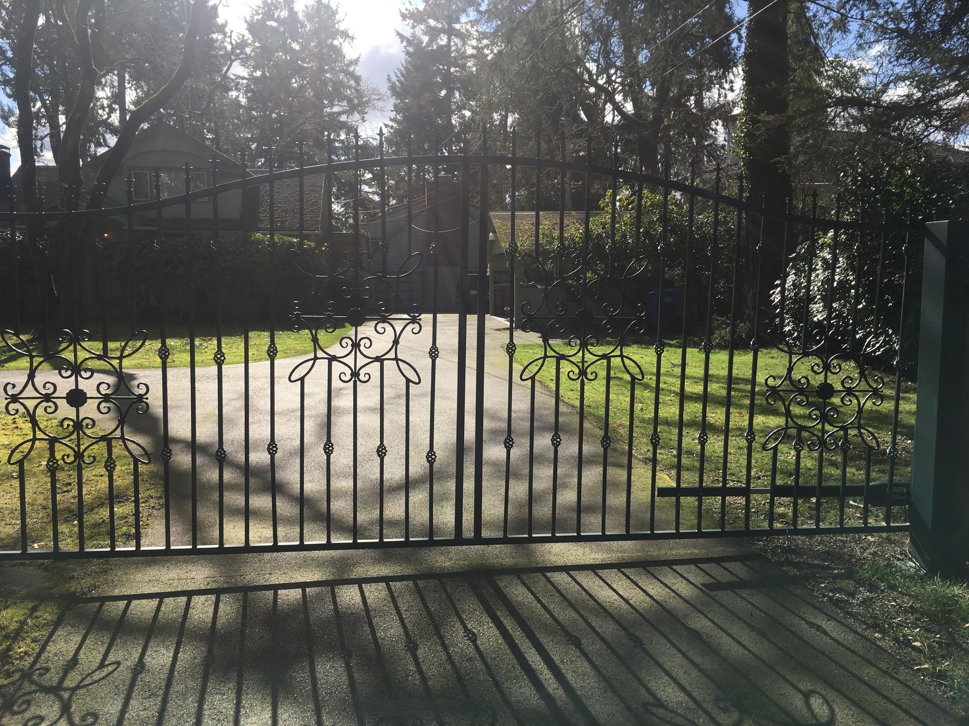 A wrought iron gate is open to a driveway